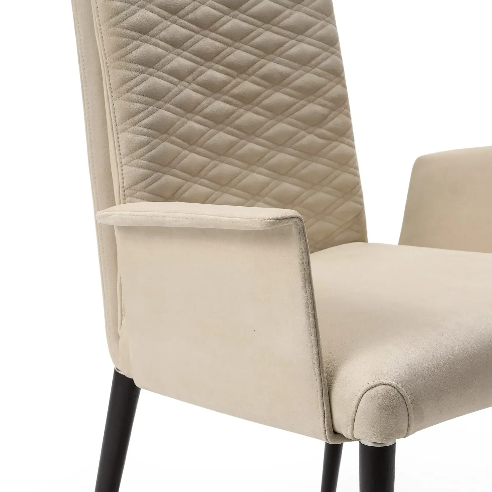 Close-up of a cream-colored chair with a diamond-quilted backrest, smooth armrests, and dark legs on a white background.