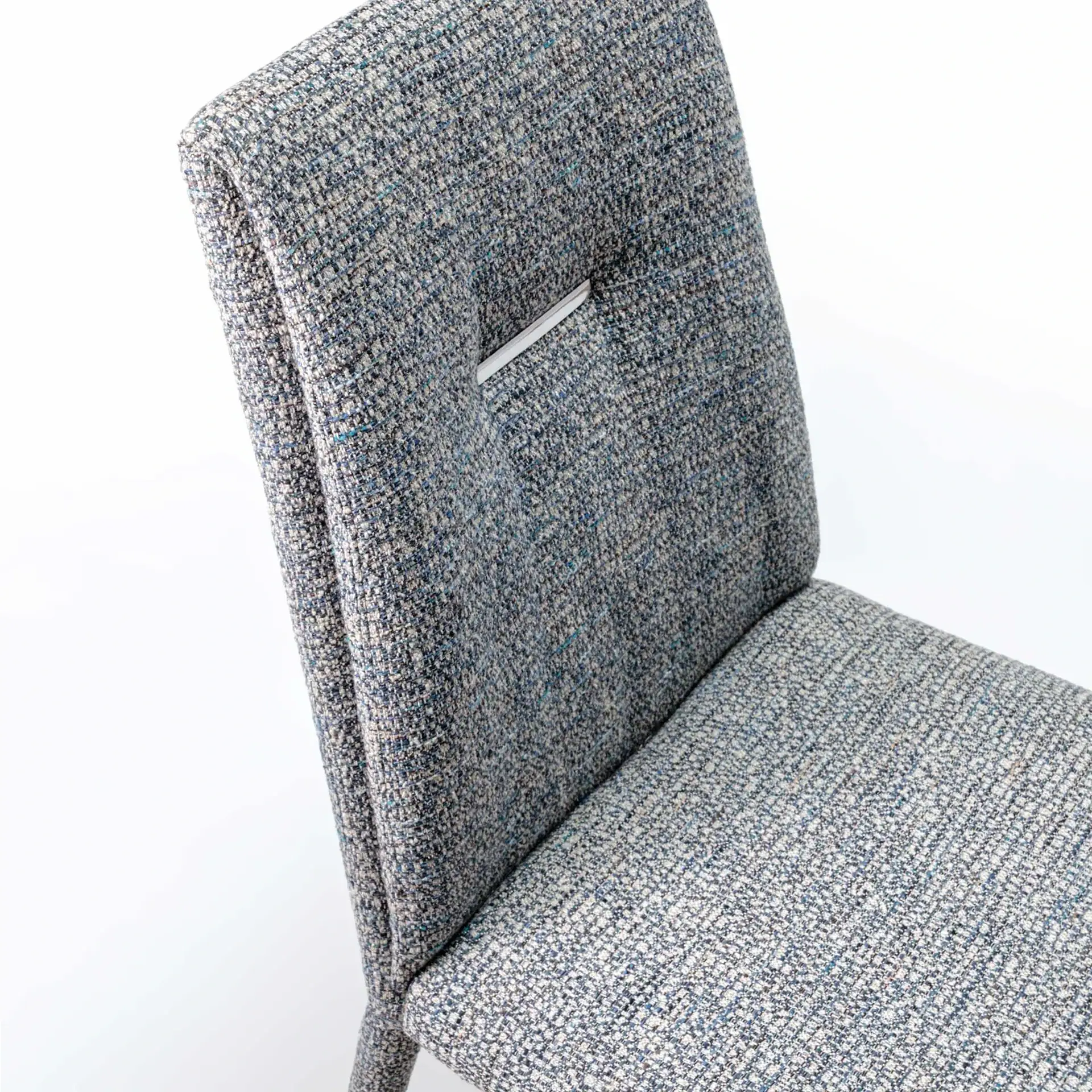Close-up of a modern chair upholstered in a textured grey and blue fabric, with a small decorative accent on the backrest.
