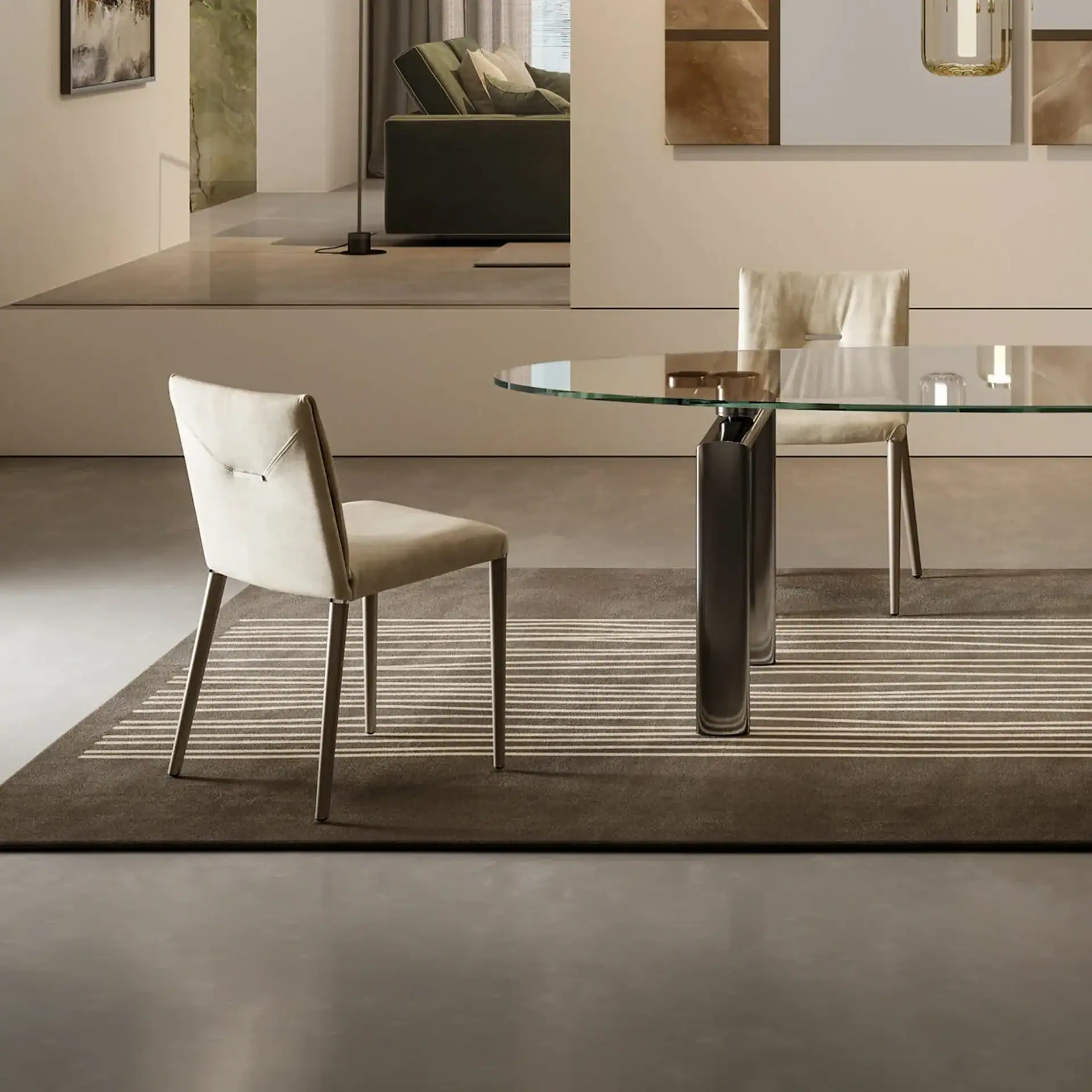 A modern dining room with a glass table, two light-colored chairs, and a striped rug, with a view into a contemporary living room with a green sofa.