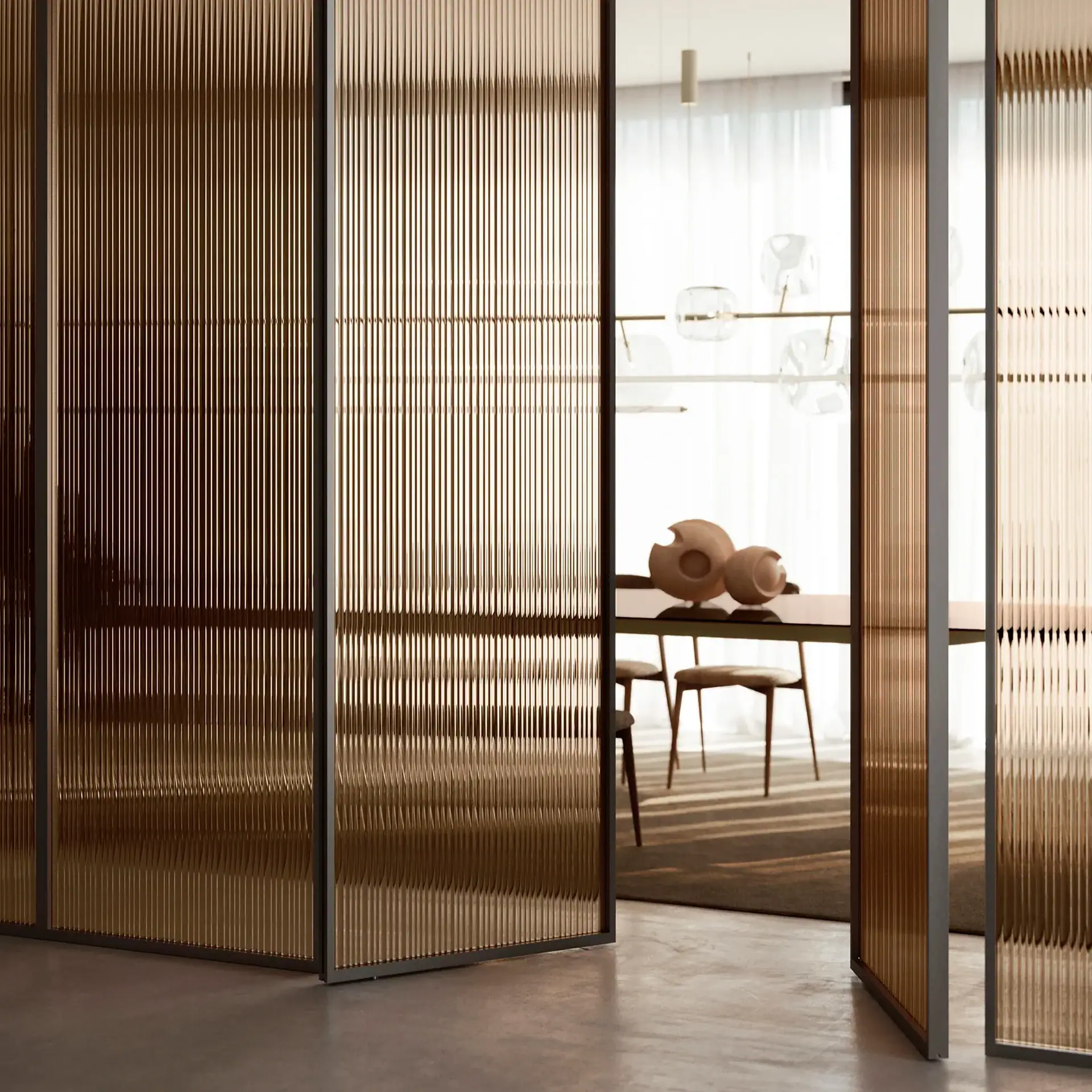 Modern interior with amber-toned fluted glass partitions partially open, revealing a dining area with a wooden table, chairs, decorative objects, and spherical pendant lights.