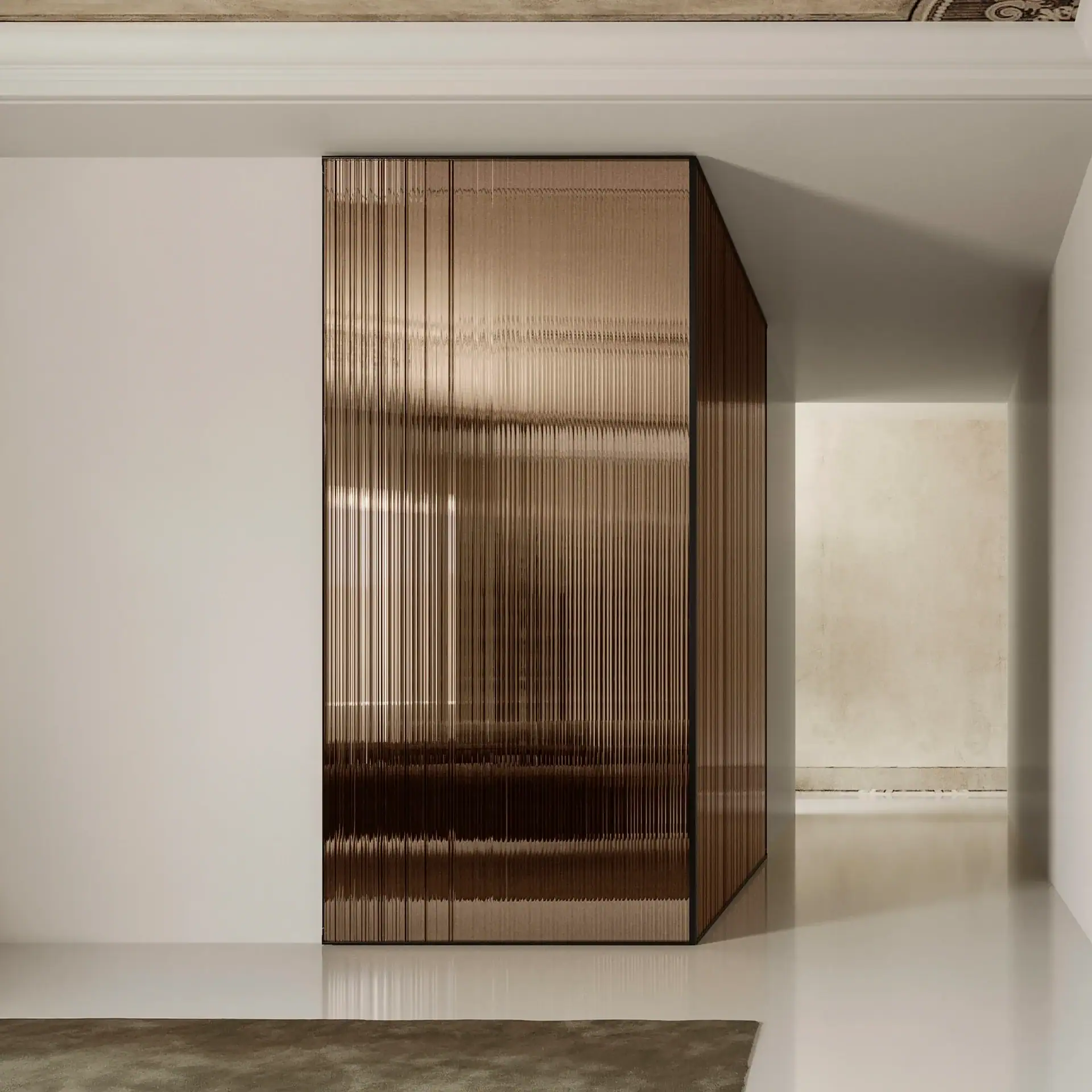 A modern room featuring a tall, angled bronze-toned fluted glass partition, separating a white wall from a light beige hallway.