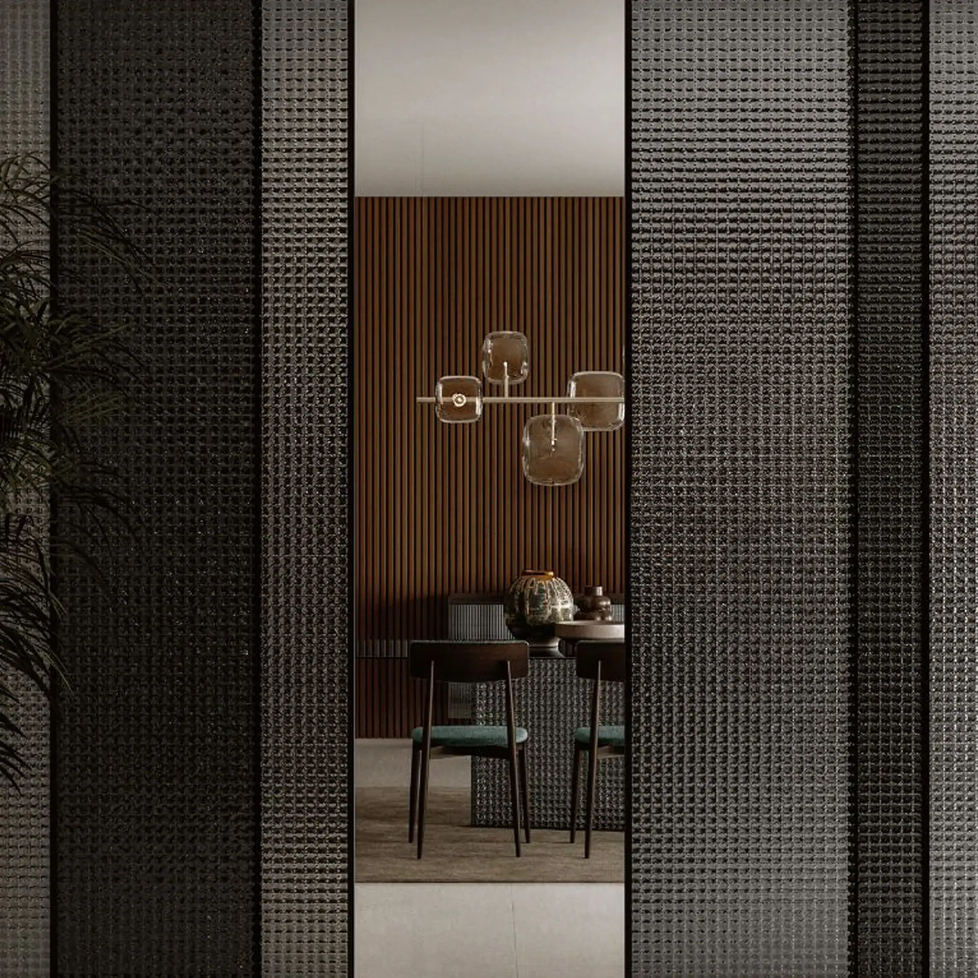 A modern dining room viewed through dark, textured glass partitions. The room features a slatted wooden wall, a unique chandelier with amber glass shades, and dark wooden chairs with teal seats around a table.