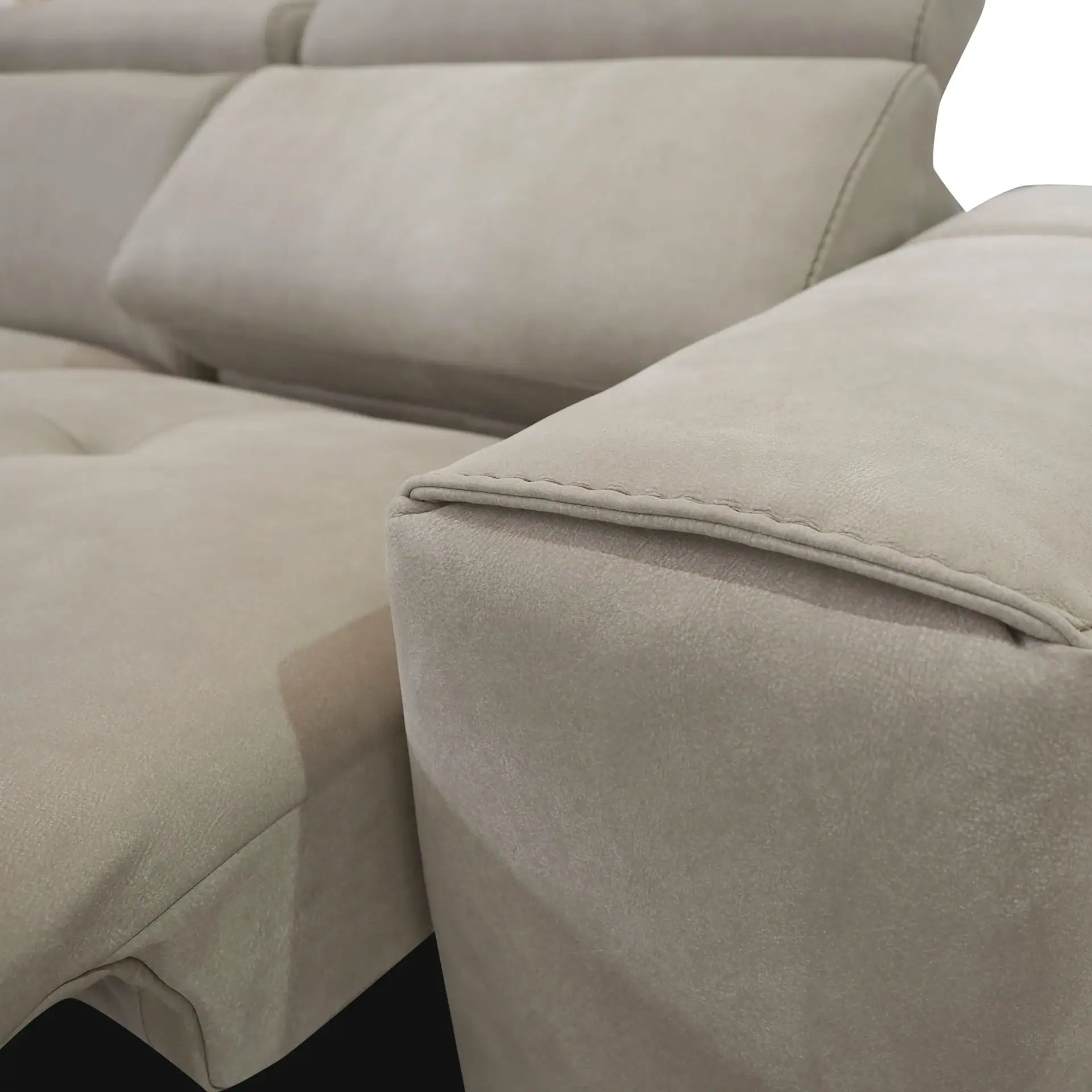 Close-up of a light beige sofa armrest and cushions, showing fabric texture and stitching details.
