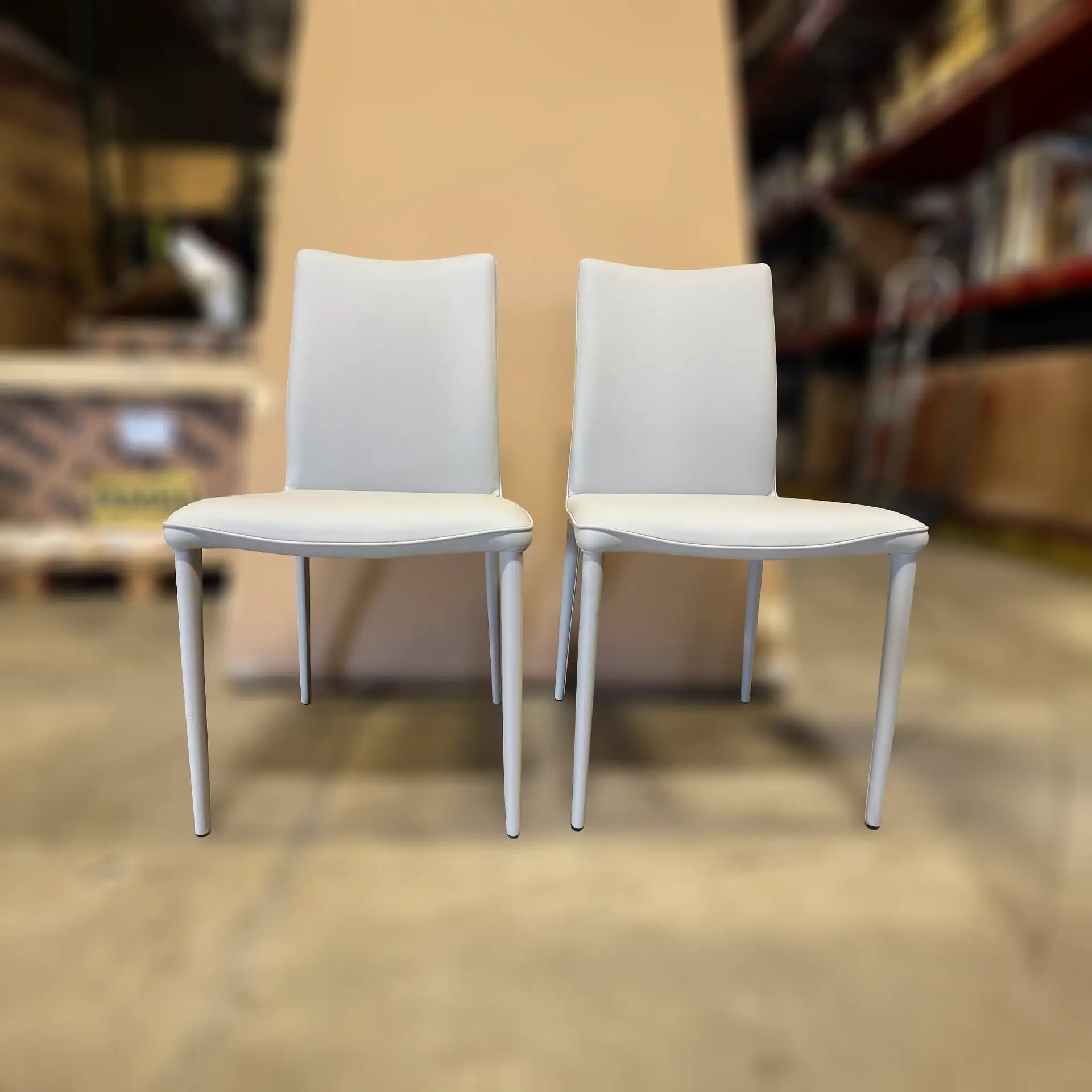 Shefi Quilted Dining Chairs pair with white upholstery and metal legs in a store setting.