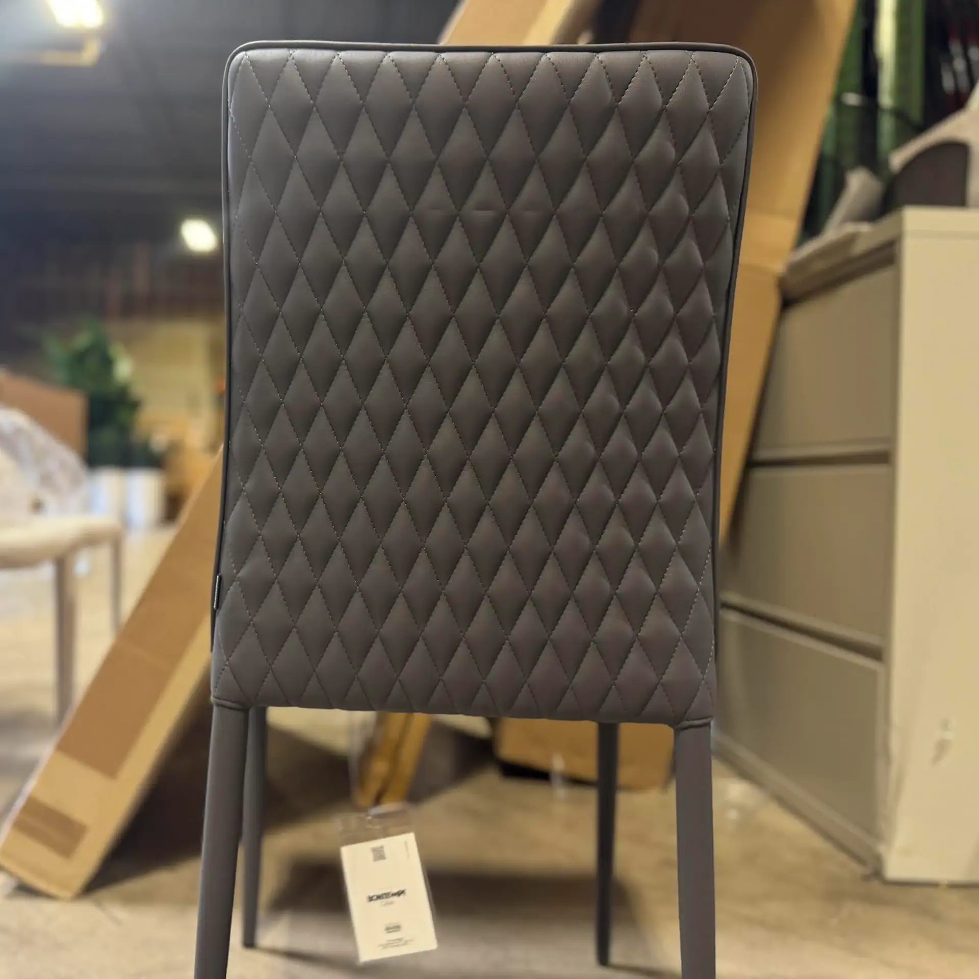 Sklar Furnishings quilted dining chair with black legs in a showroom.