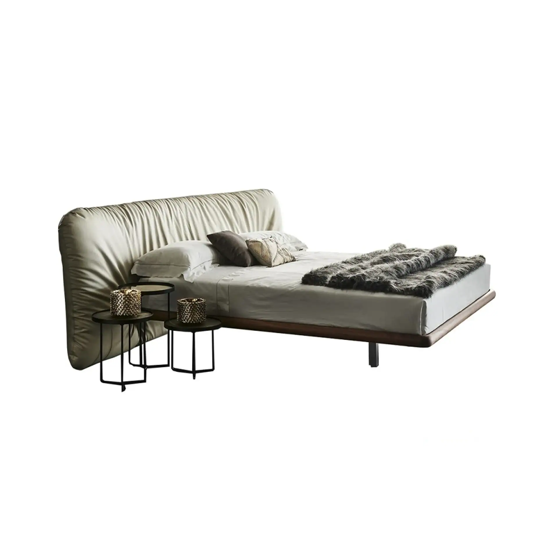 A modern bed with a light beige pleated headboard, white bedding, a grey faux fur throw, and two black hexagonal side tables with gold decorative objects.