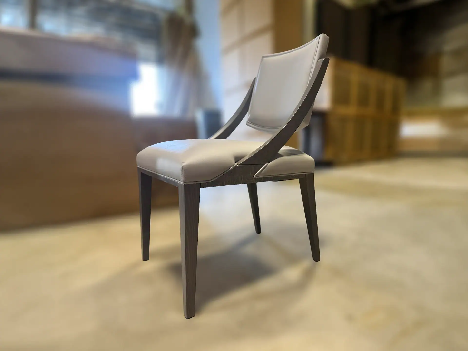A modern dining chair with light beige upholstery and a dark, curved wooden frame, sitting on a light floor.