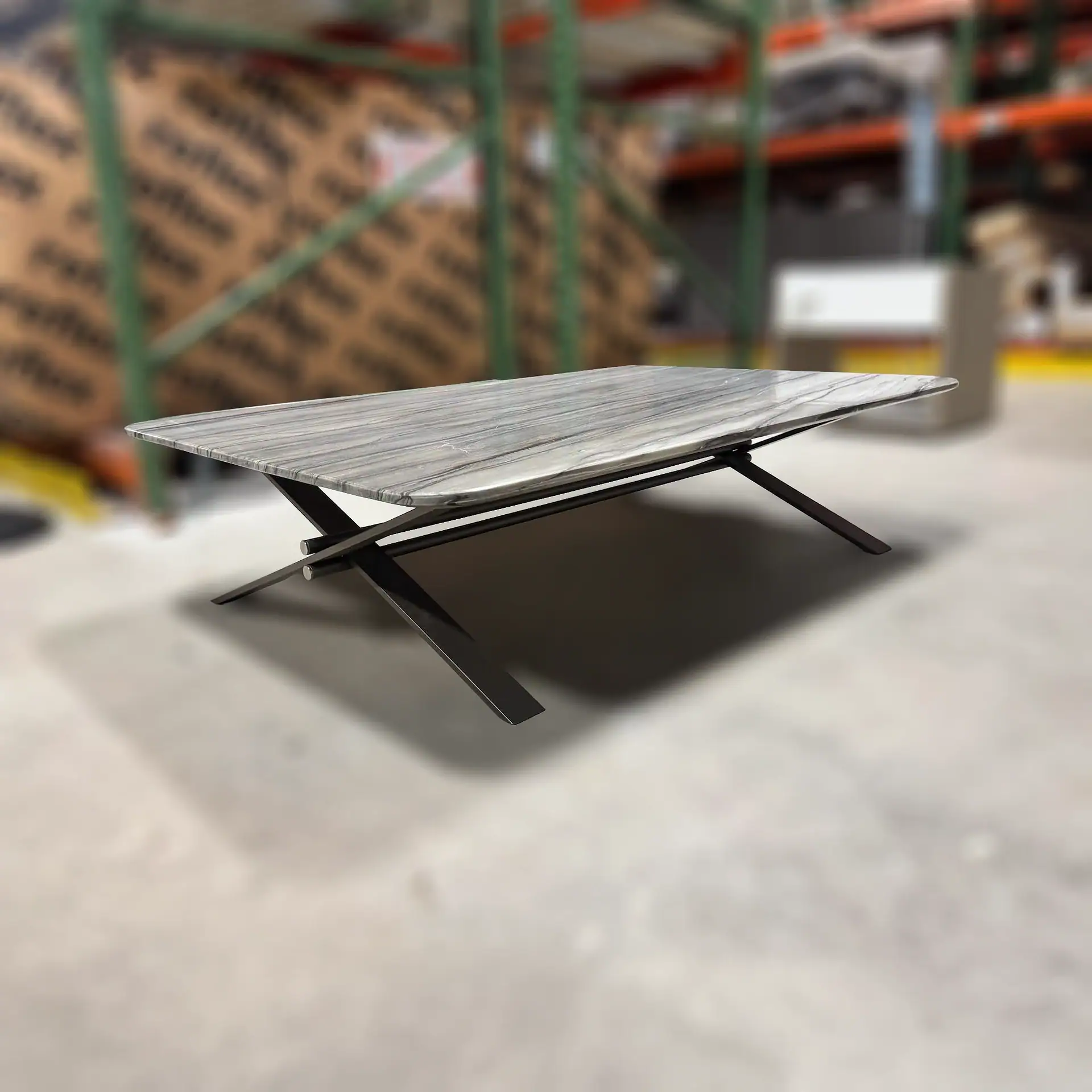 Sklar Furnishings coffee table with a marble top and black metal legs in a warehouse.