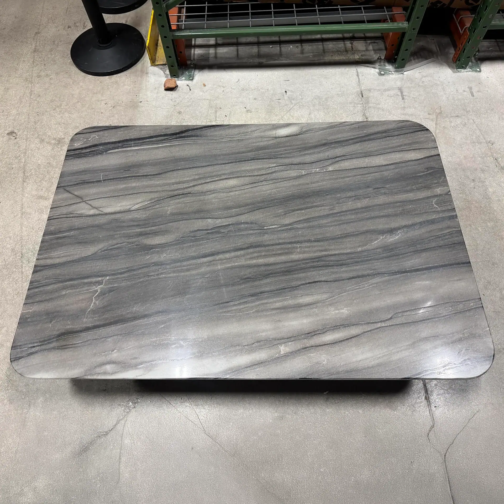 Sklar Furnishings coffee table with a marble finish in a warehouse setting.