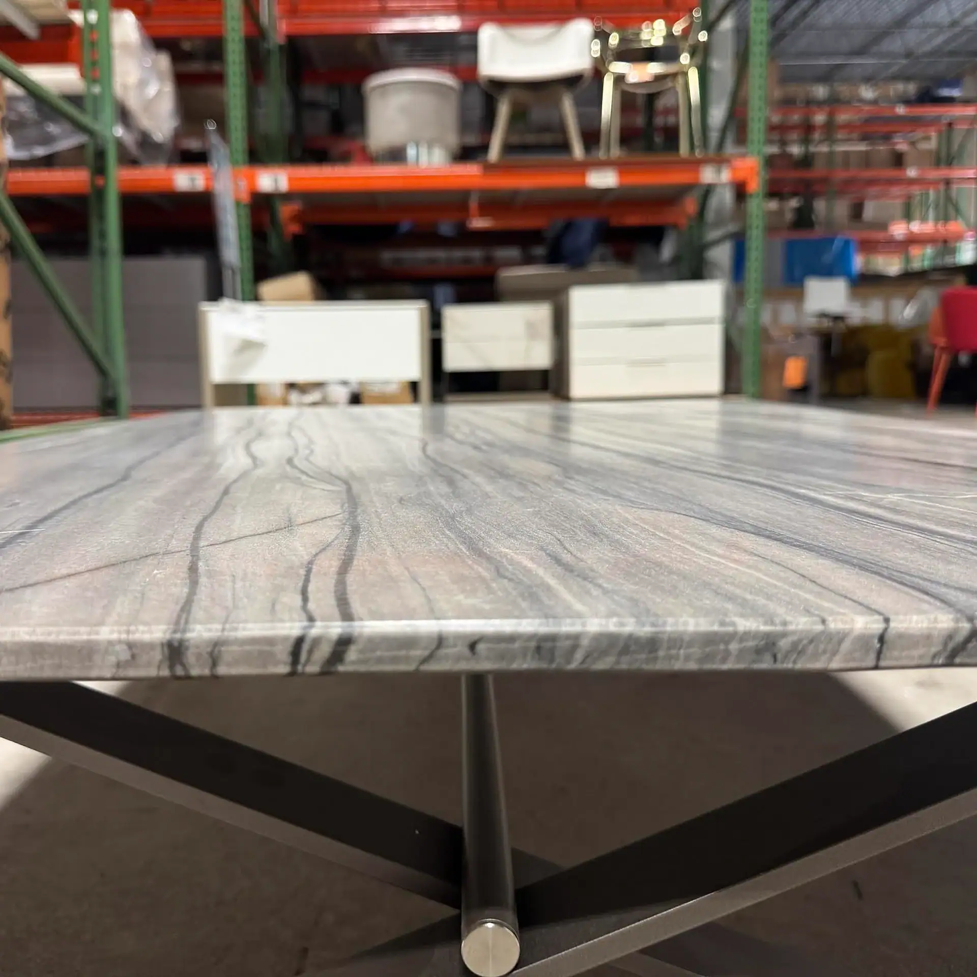 Sklar Furnishings coffee table with marble top in warehouse setting.