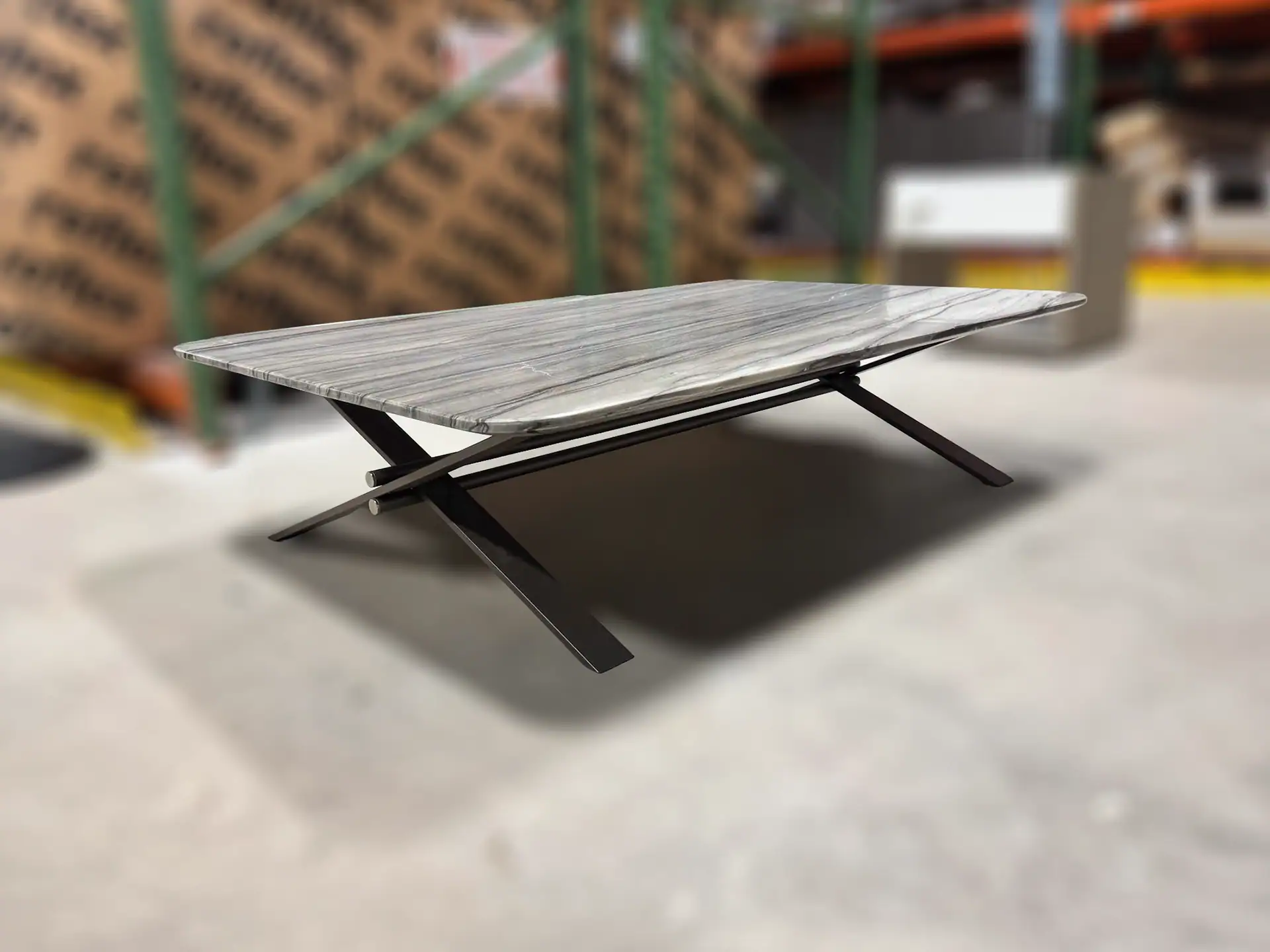 Sklar Furnishings coffee table with a wooden top and black metal legs in a warehouse.