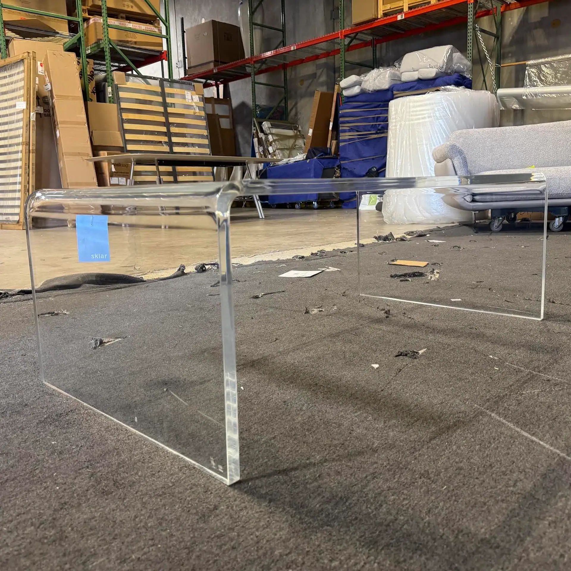Sklar Furnishings acrylic coffee table in warehouse setting.