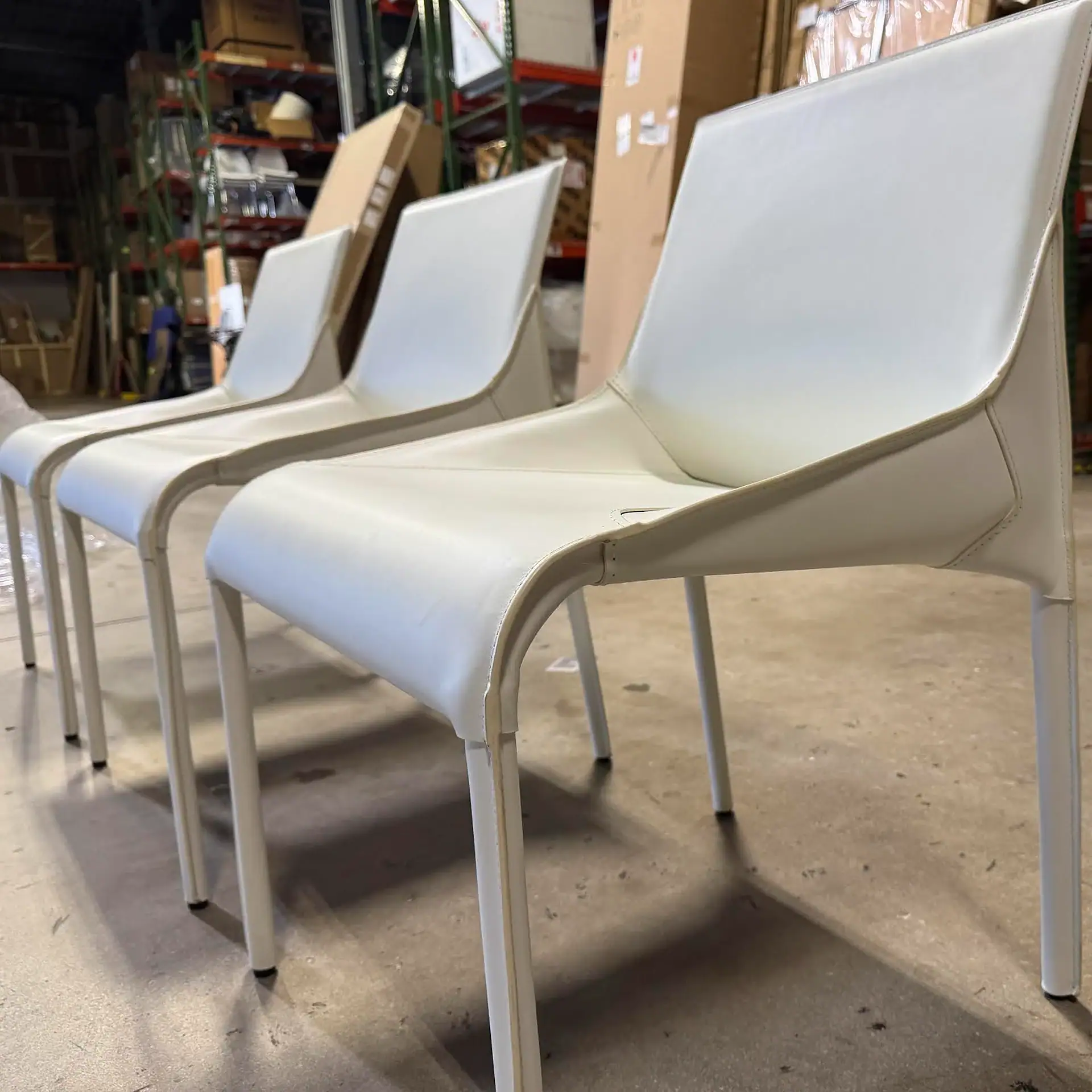 Three Nuevo Colter dining chairs in a warehouse setting.
