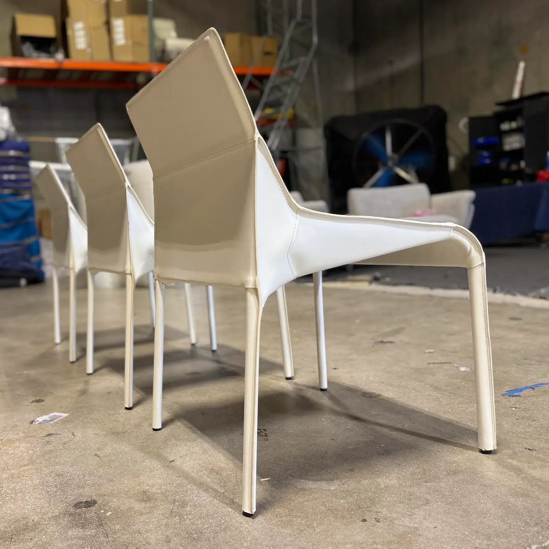 White Nuevo Colter dining chairs in a warehouse setting.