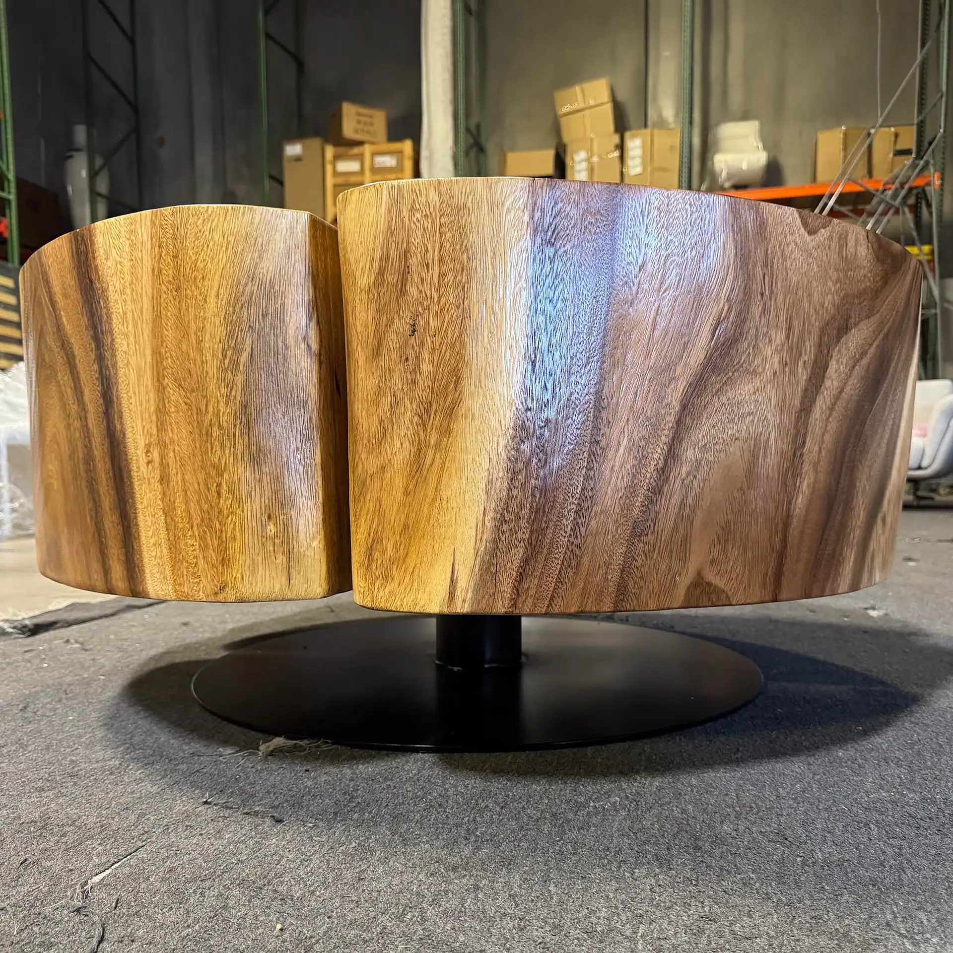 Sklar Furnishings wooden coffee table with a rounded design in a warehouse setting.