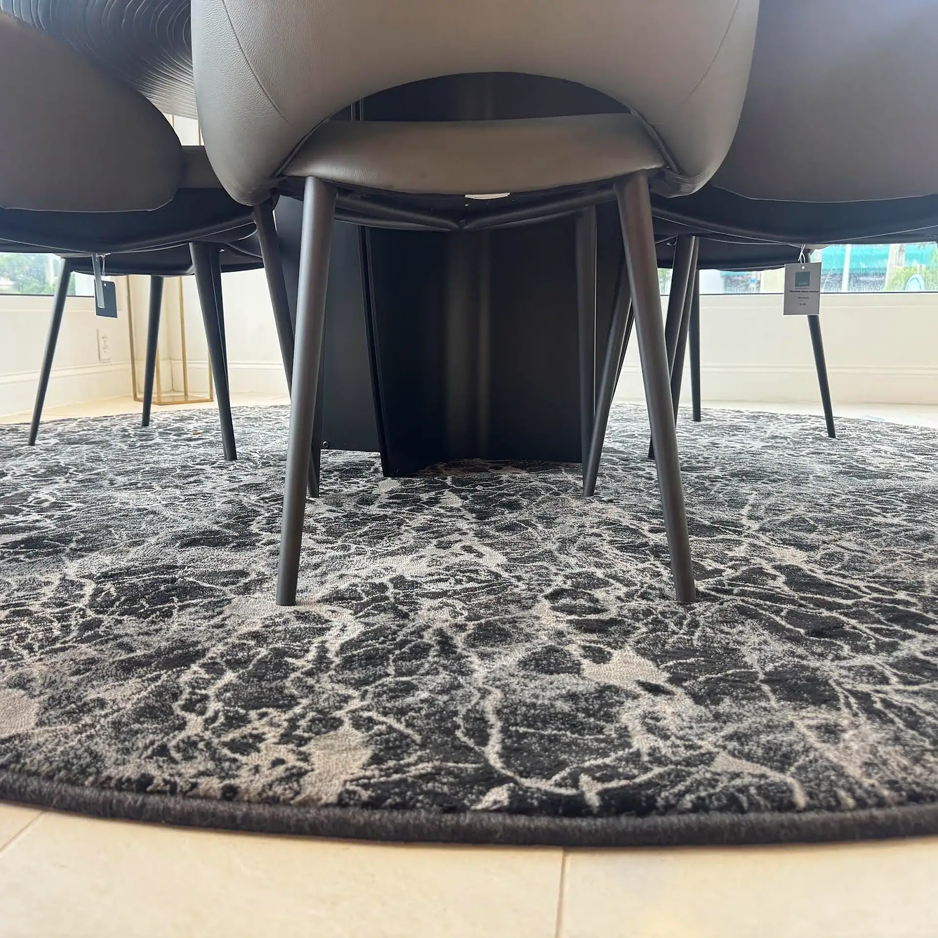 Close-up of Stanton Zeus round rug with black and gray pattern under chairs.