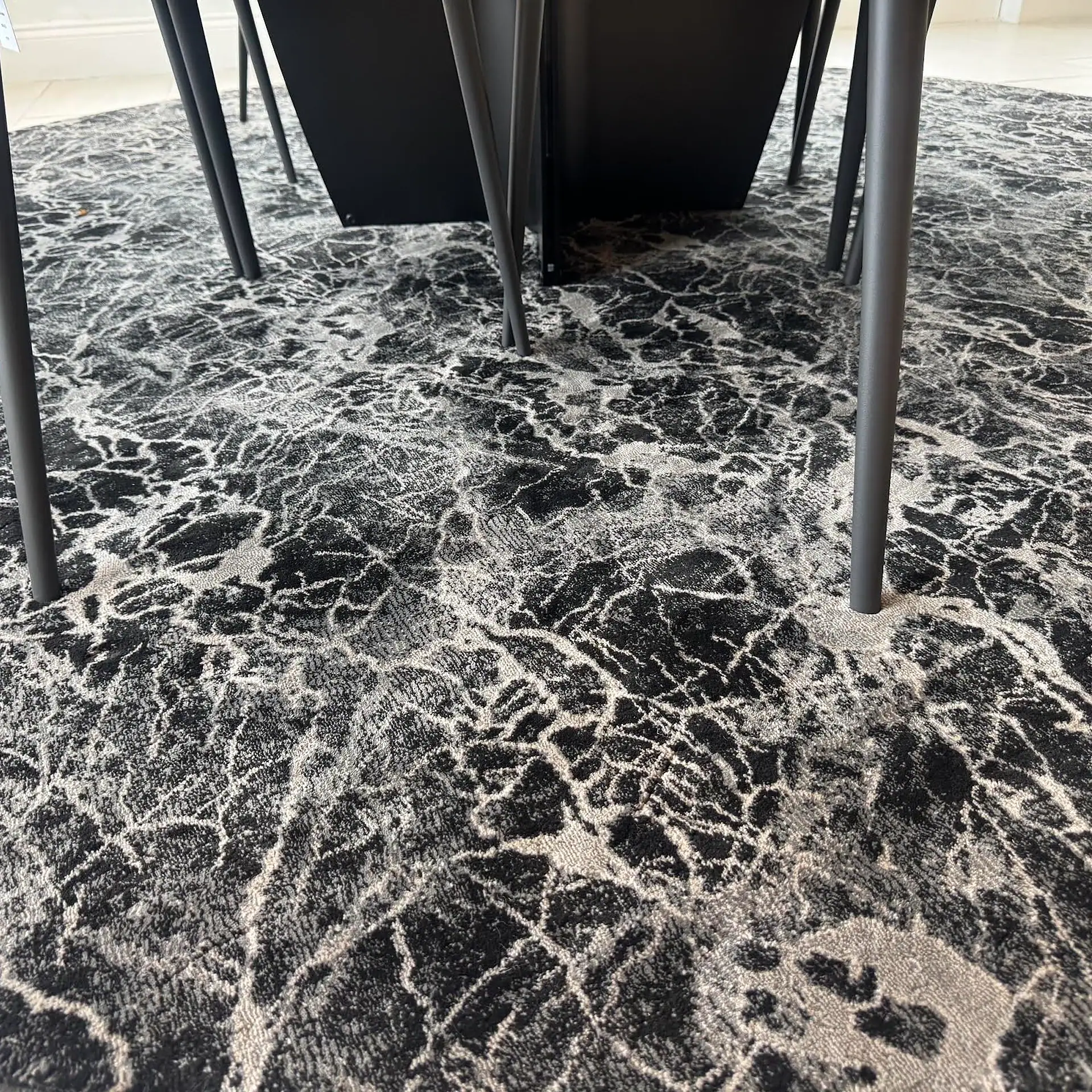 Stanton Zeus Round Rug with black and white abstract pattern under table legs.