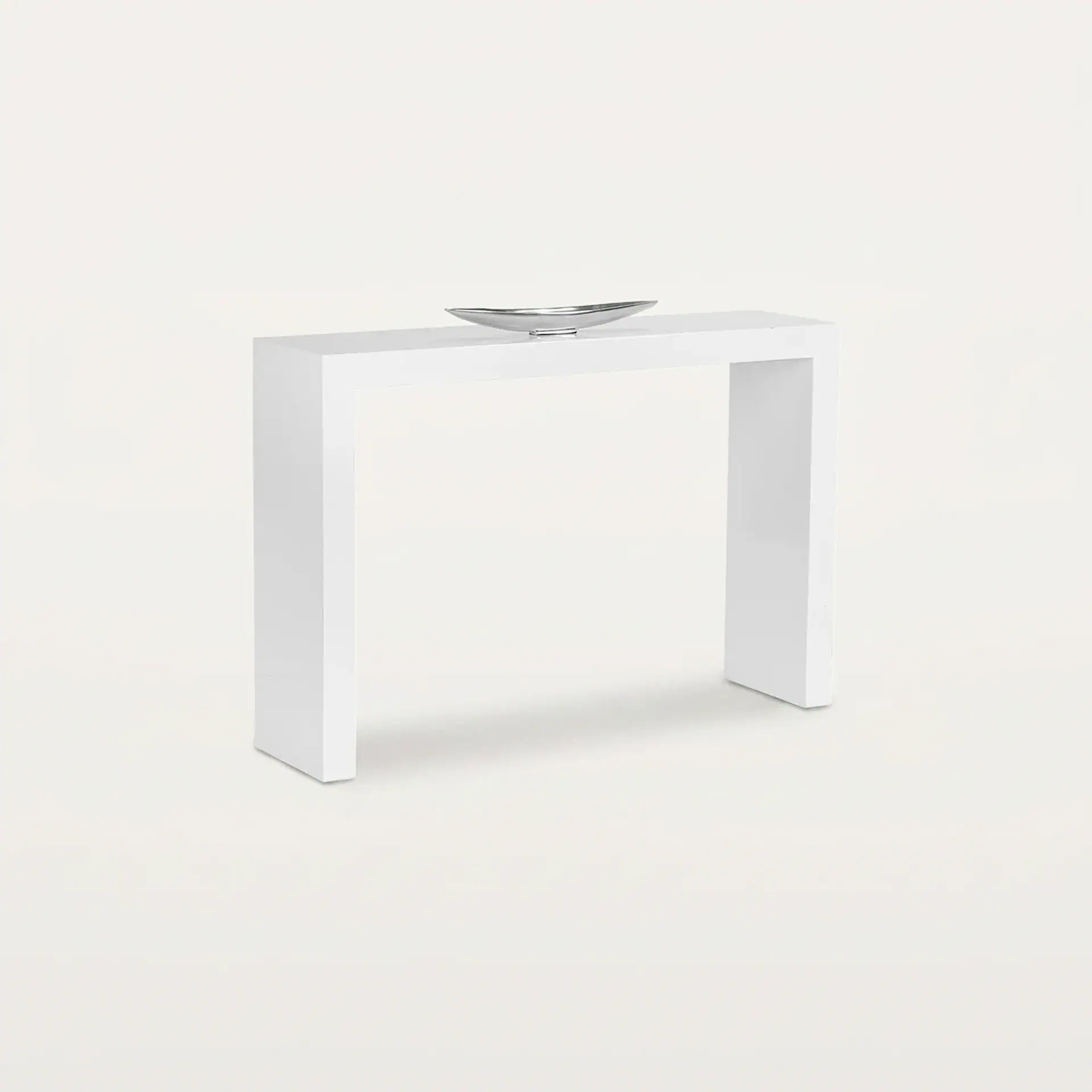 A white minimalist console table with a silver boat-shaped decorative bowl on top, set against a light background.
