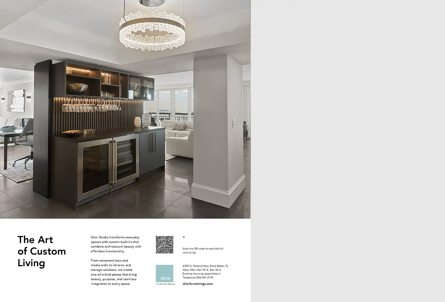 A modern built-in bar with dark cabinetry, beverage coolers, and glassware, illuminated by a crystal chandelier in an open-concept living space.