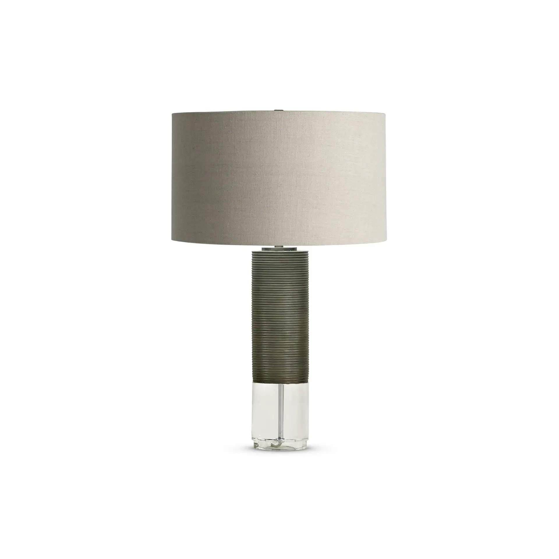 Modern table lamp with a light gray fabric drum shade, a dark gray ribbed cylindrical base, and a clear glass lower section.