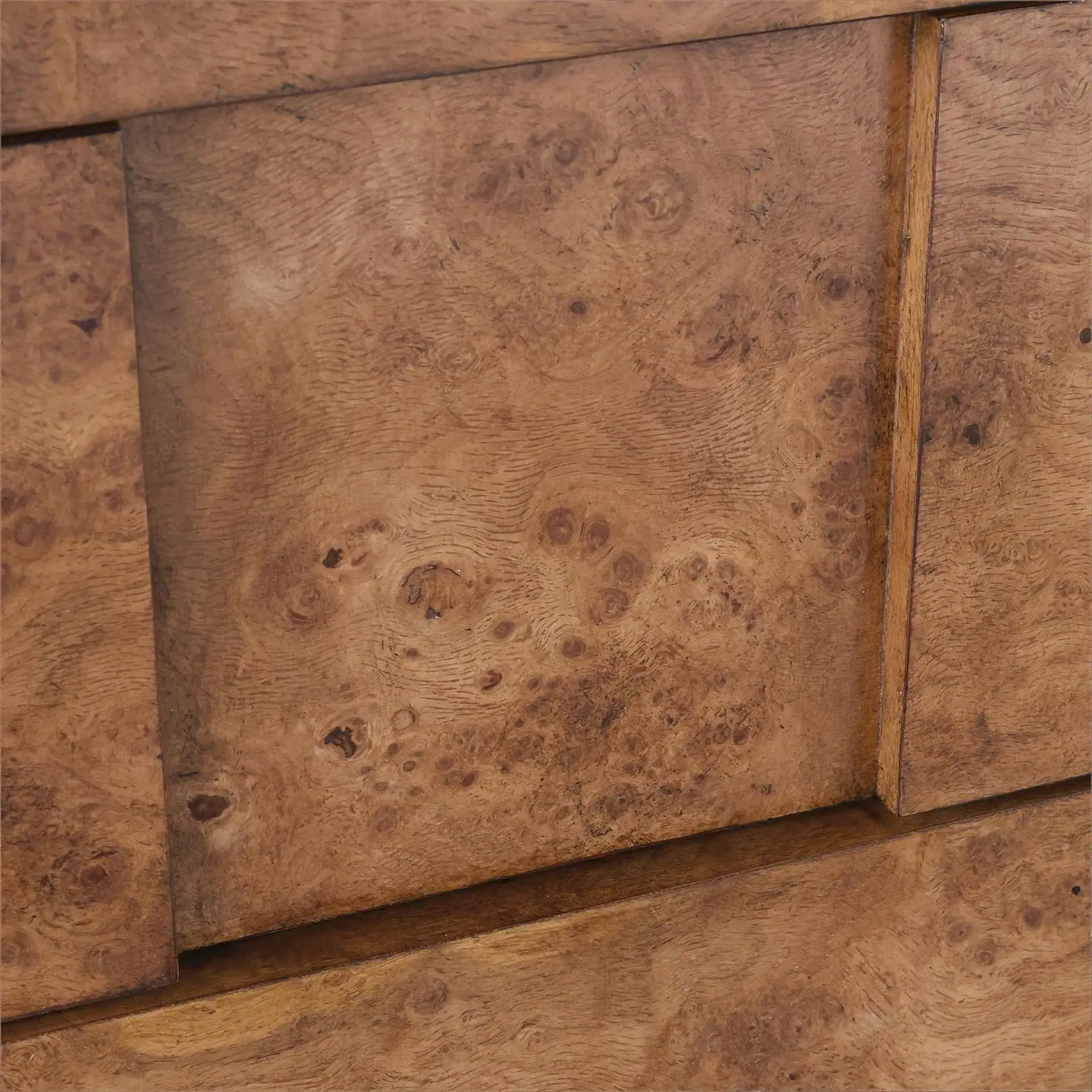 Close-up of a brown burl wood surface with intricate swirling grain patterns and visible seams between panels.
