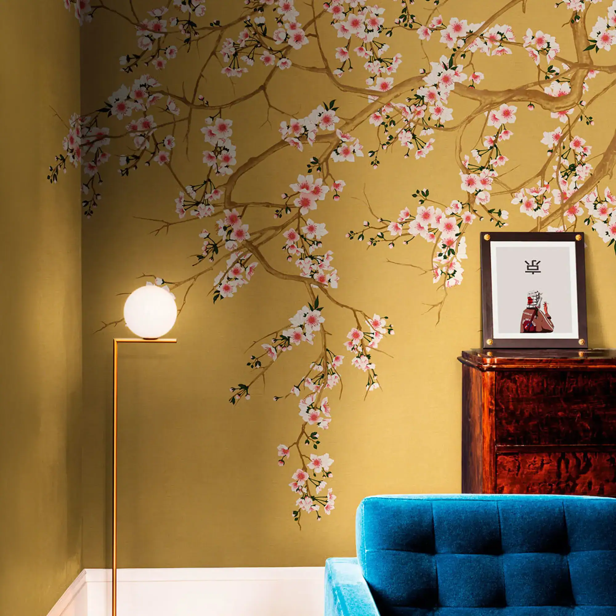 Cherry blossom branch wallpaper in a room with a blue sofa and framed art.