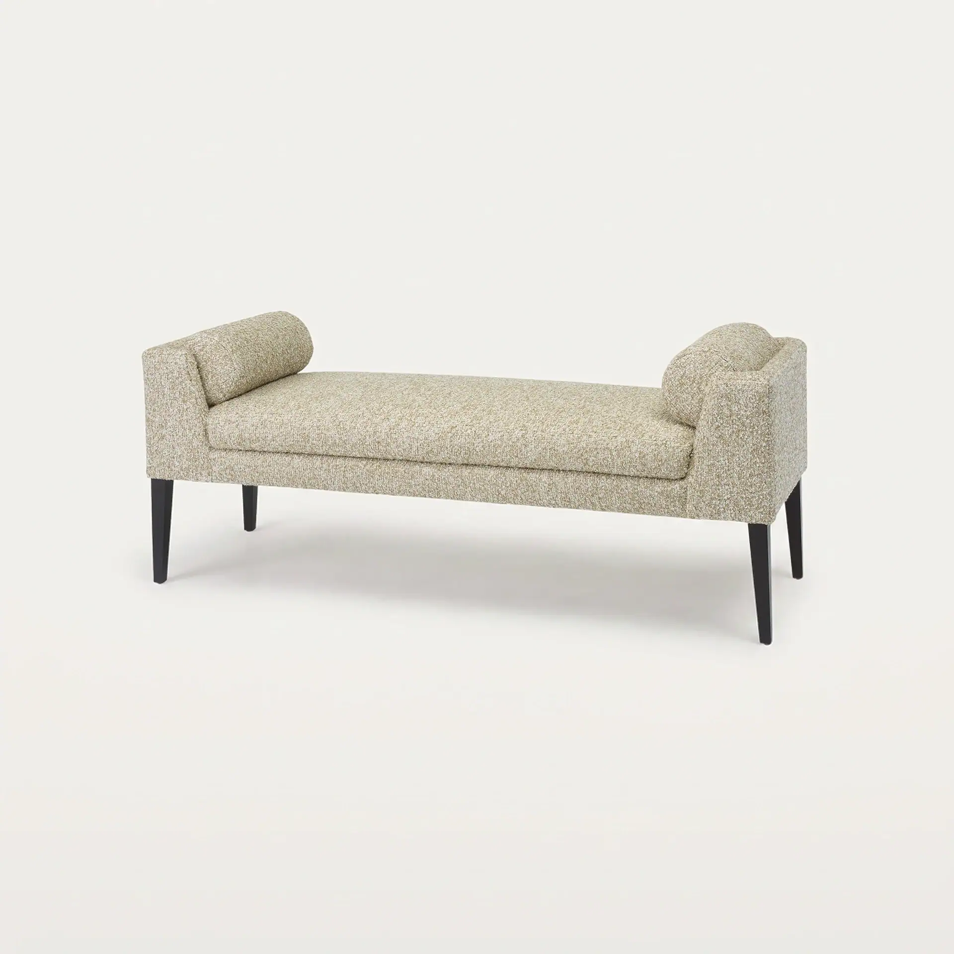 A long, light beige upholstered bench with rolled armrests and dark tapered legs on a white background.