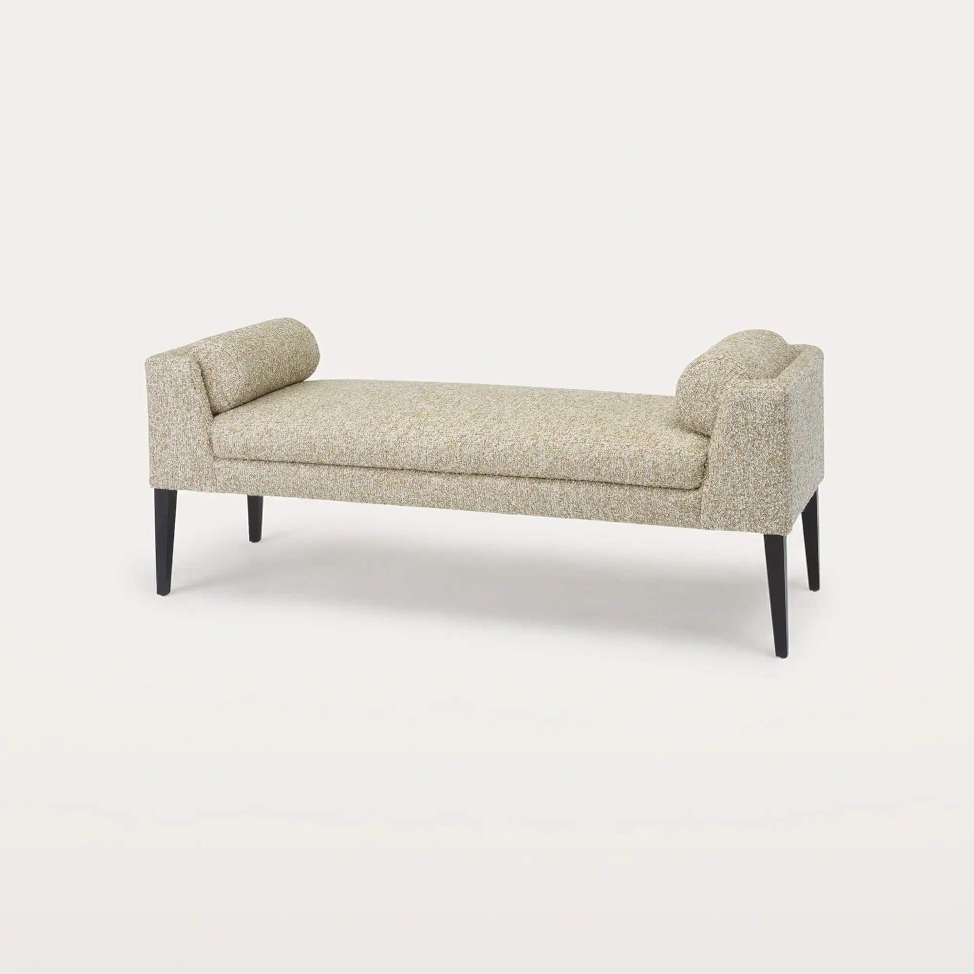 A long, light beige upholstered bench with rolled armrests and dark tapered legs on a white background.