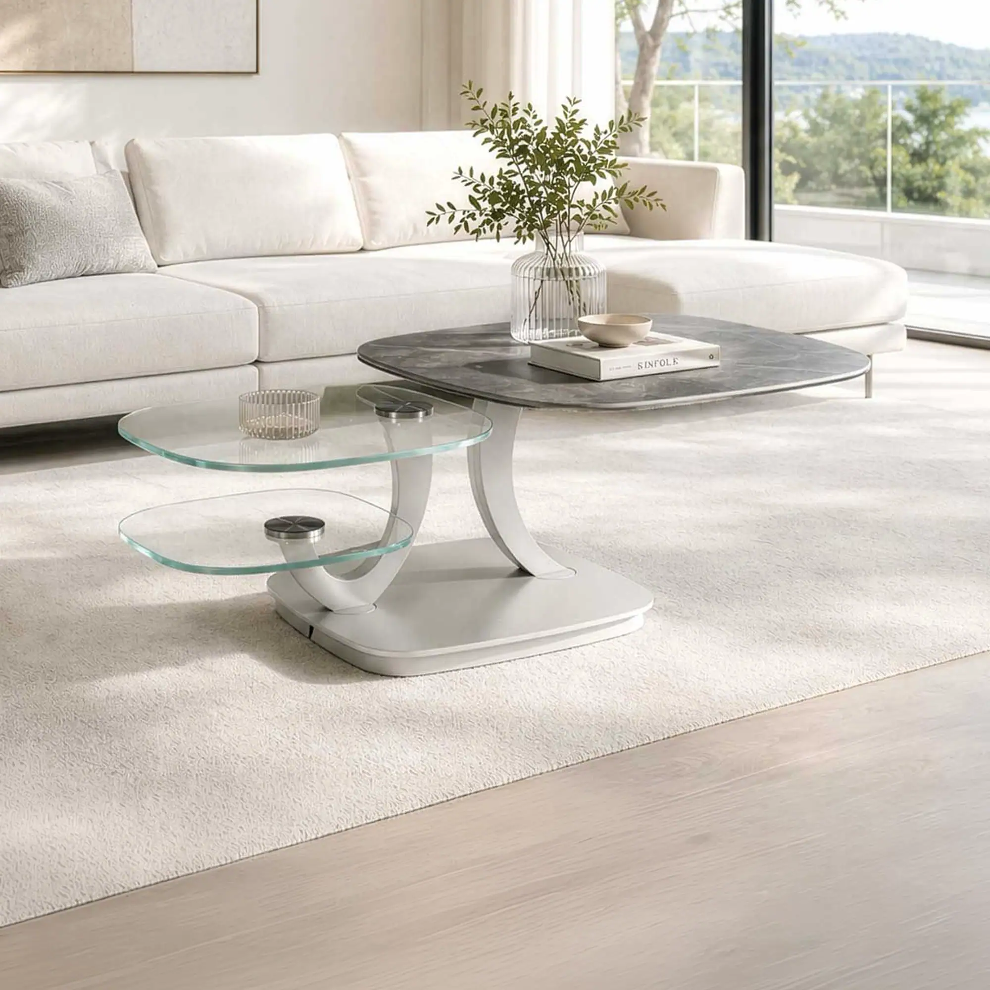 A modern living room with a multi-tiered coffee table, a cream sectional sofa, and large windows overlooking a green landscape.