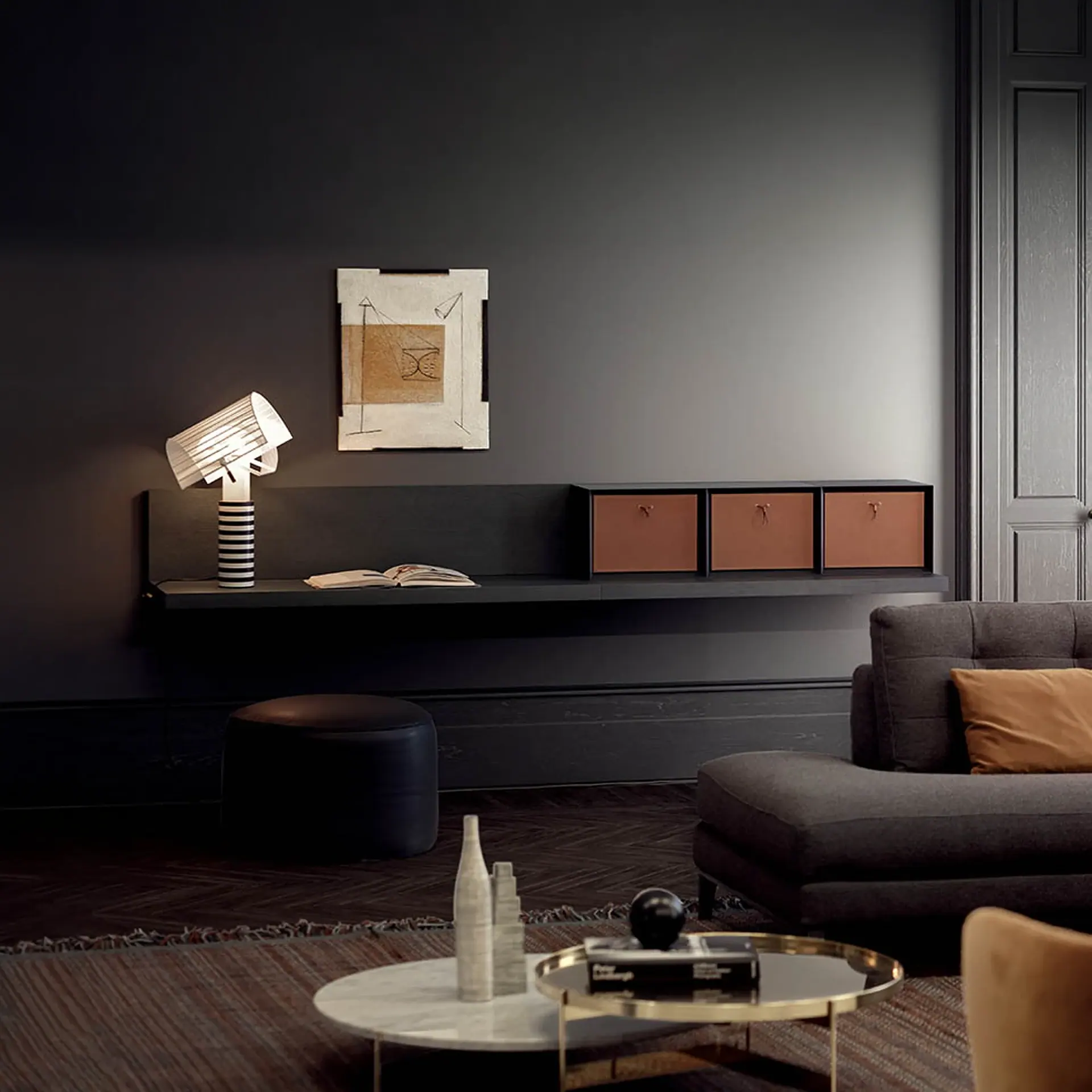 A modern living room with dark gray walls, a floating console unit, a striped table lamp, abstract art, and dark furniture.