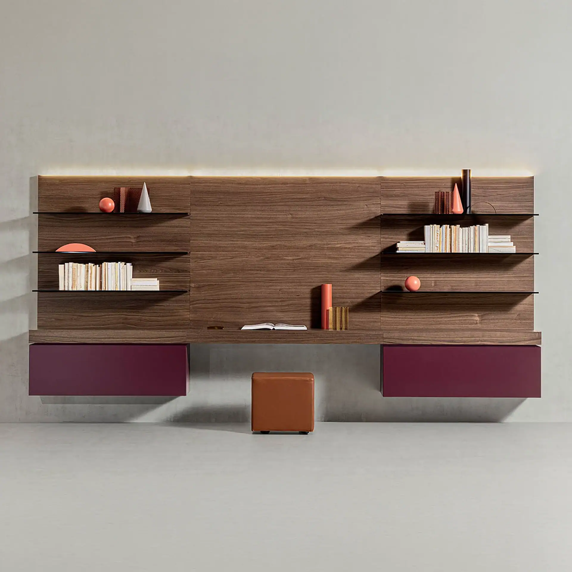 A modern wall-mounted wooden desk and shelving unit with integrated LED lighting. It features black glass shelves, reddish-purple drawers, and a brown leather stool on a light gray floor.