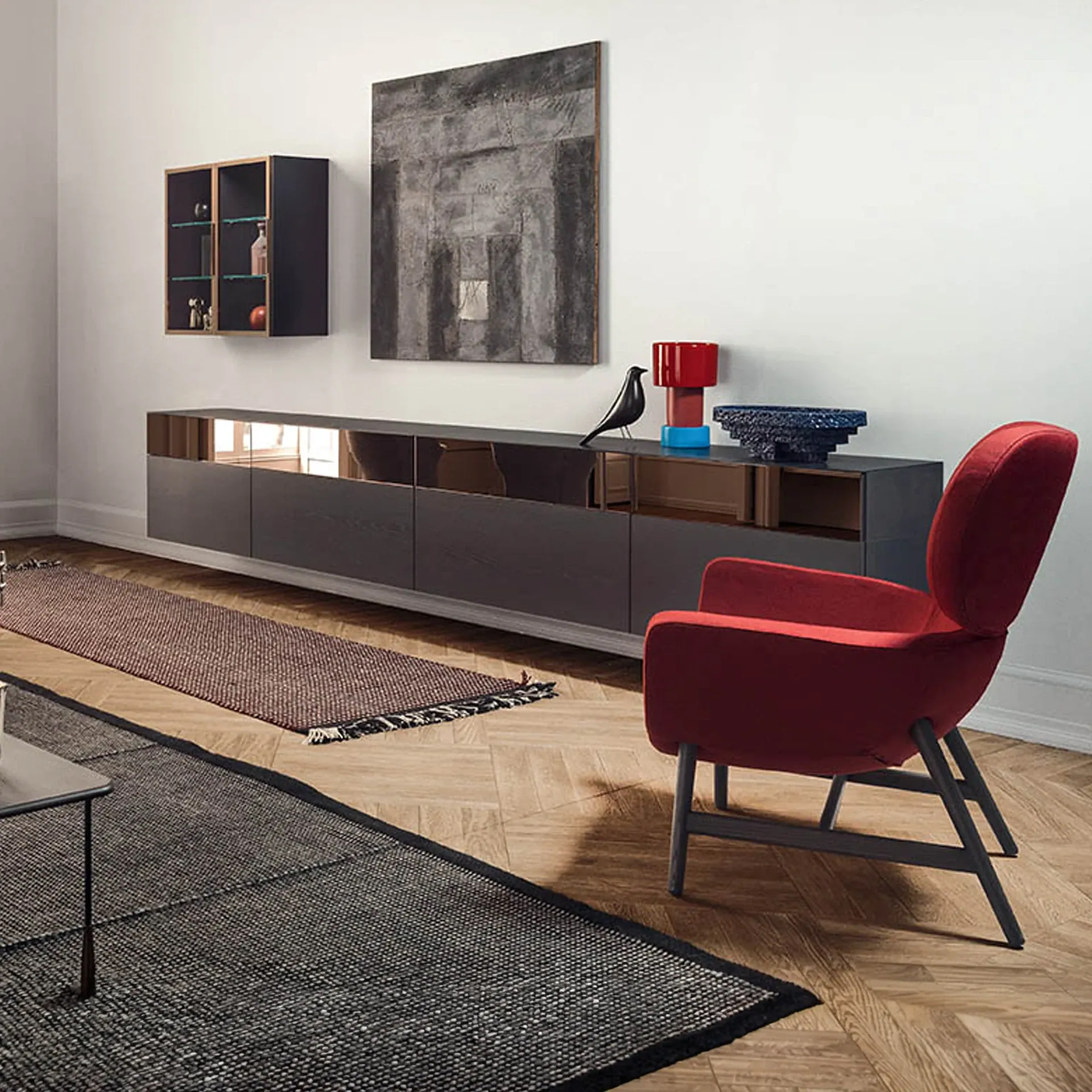A modern living room with a red armchair, dark grey console table, abstract painting, and wooden parquet flooring.