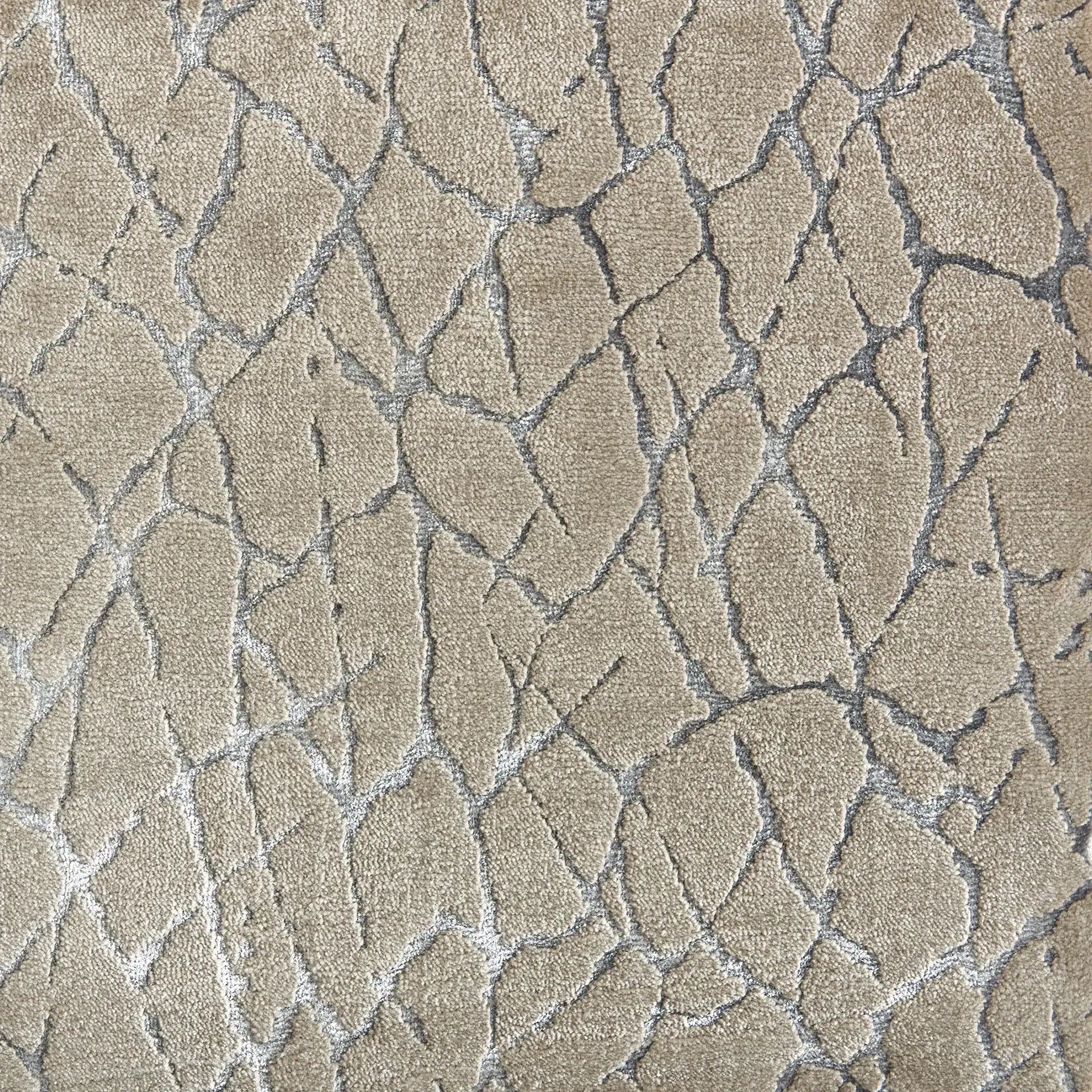Close-up of a textured fabric with an irregular, cracked pattern in light beige and silvery-grey.