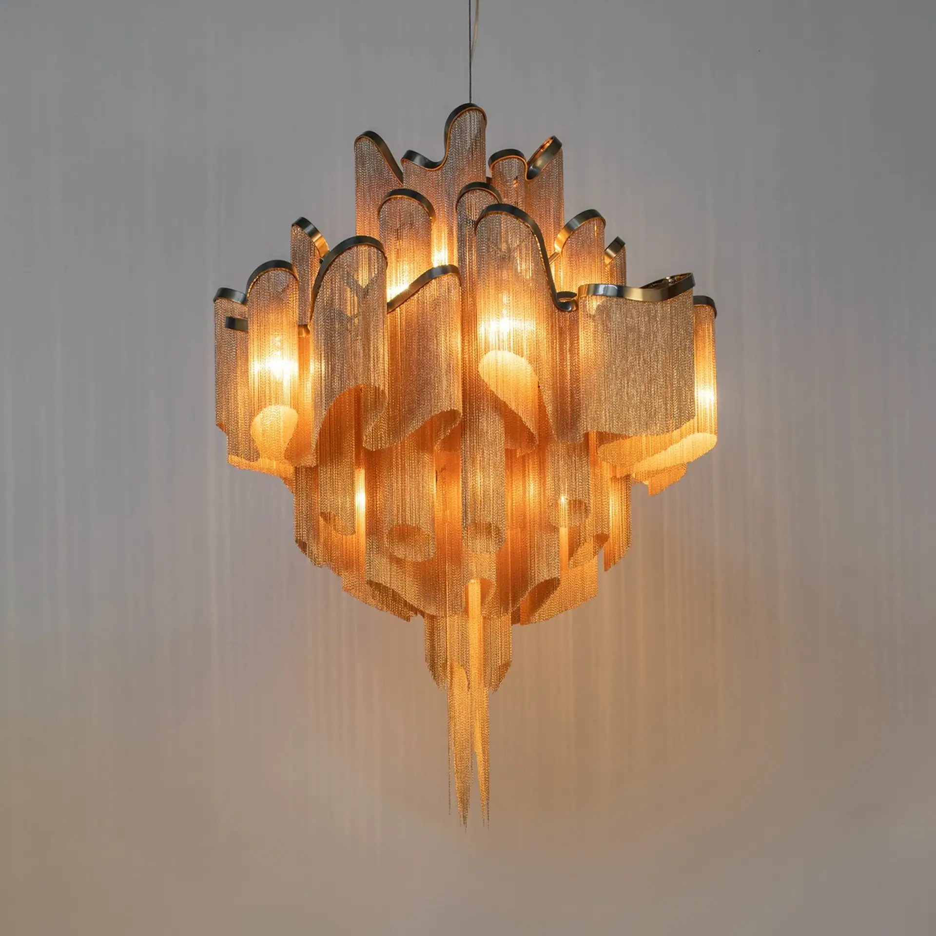 A luxurious chandelier made of golden metal chains, illuminated from within, casting a warm glow.