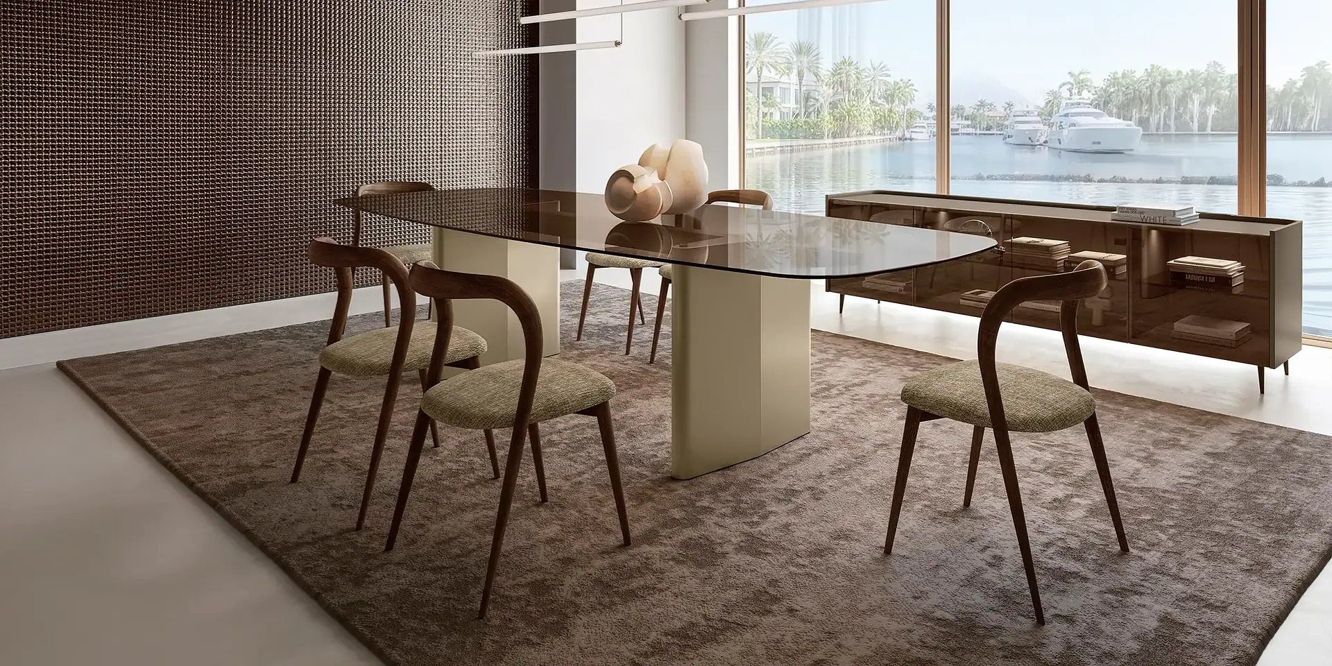 A modern dining room with a glass table, six wooden chairs, a textured wall, and a large window overlooking a waterfront with boats and palm trees.