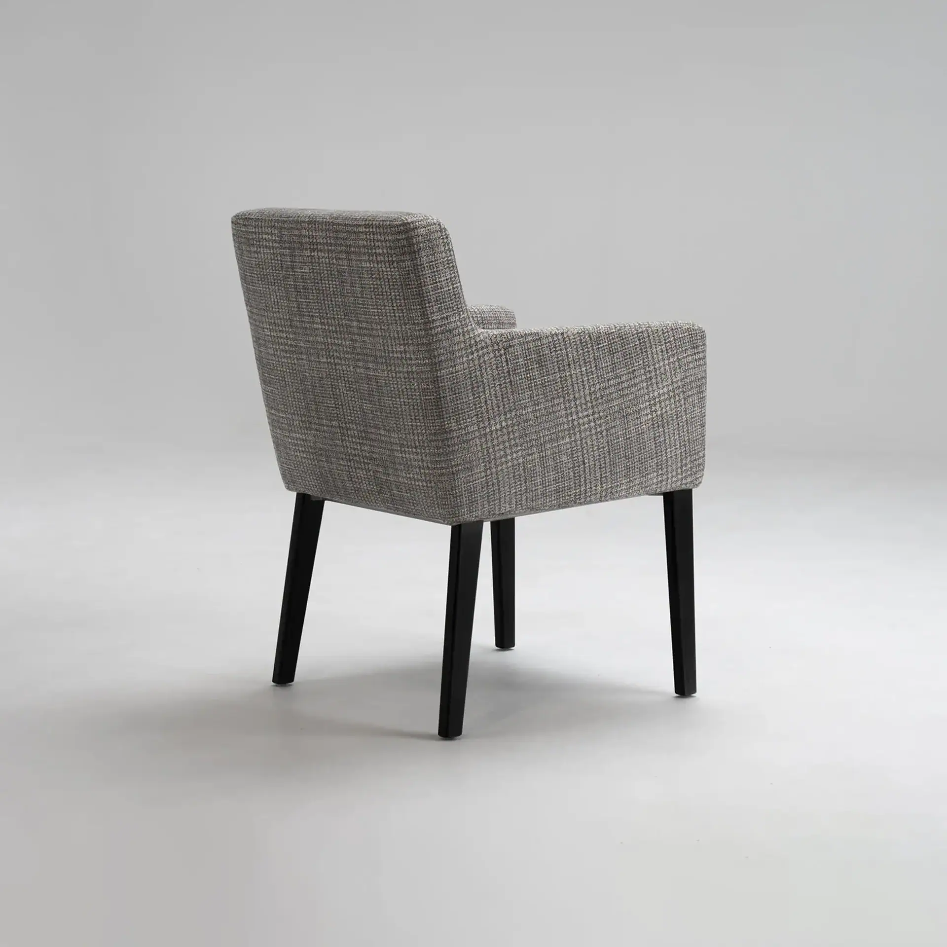 Gray upholstered armchair with dark legs, viewed from the back-side angle on a light gray background.
