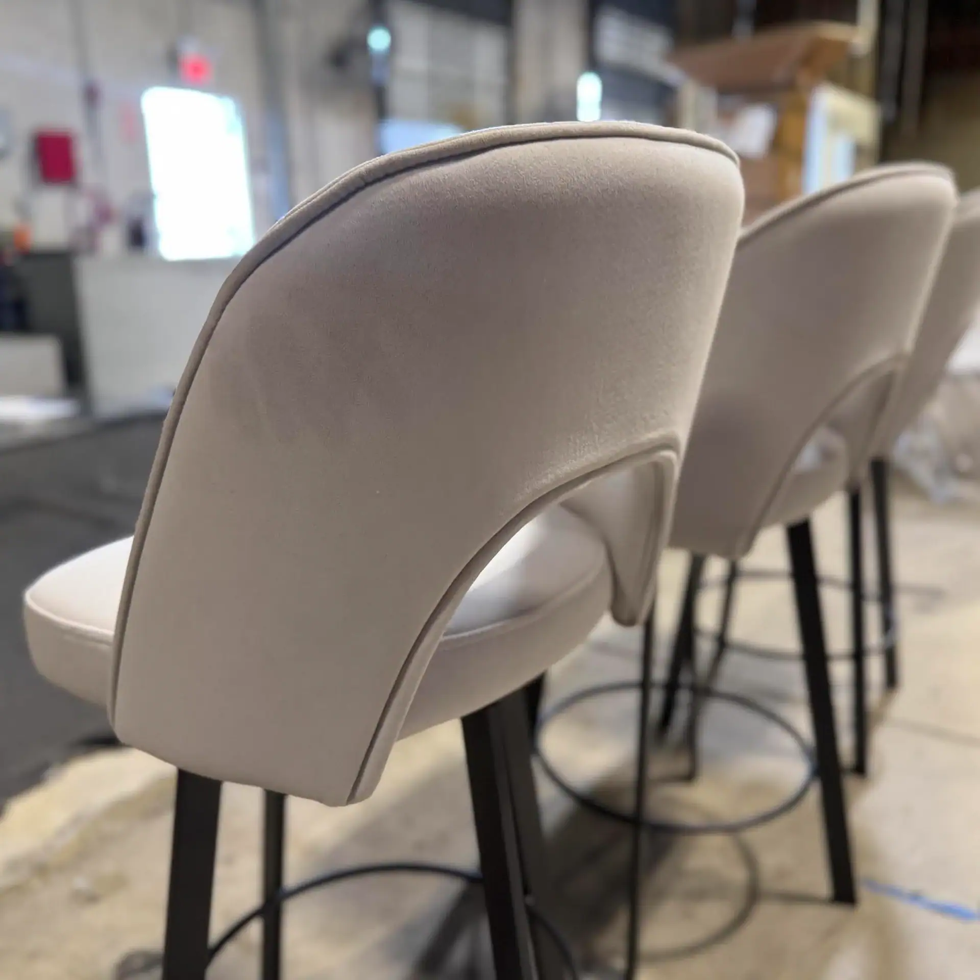 Trica Mia swivel counter stool with beige upholstery and black legs.