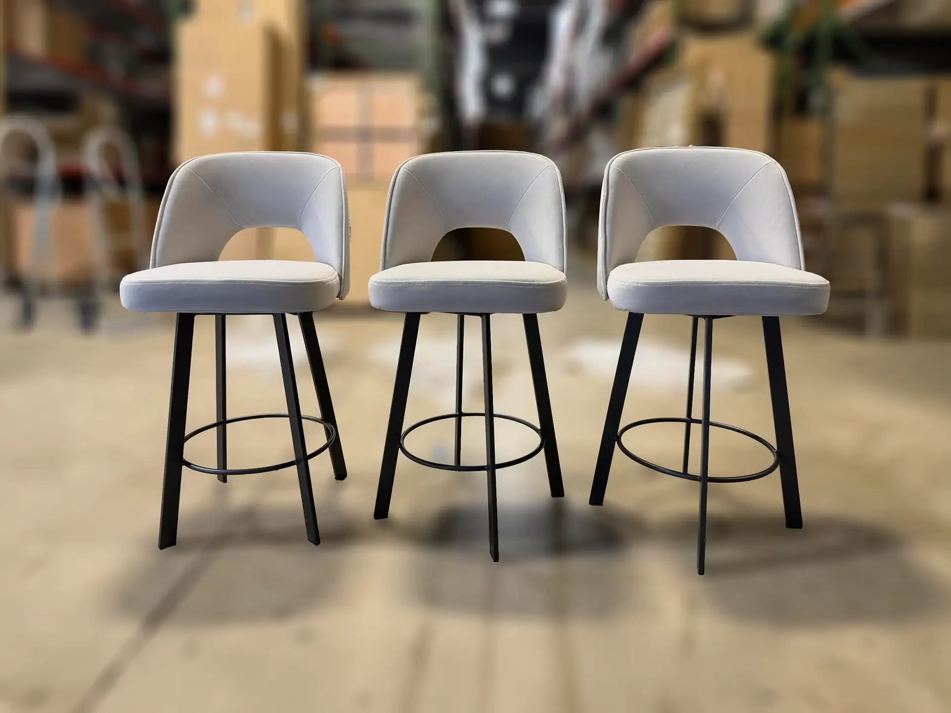 Sklar Furnishings Mia swivel counter stool three in a row in a warehouse.