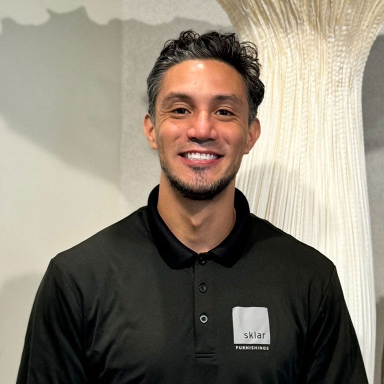 Man with dark hair and goatee in a dark polo shirt with 'Sklar Furnishings' logo, smiling.