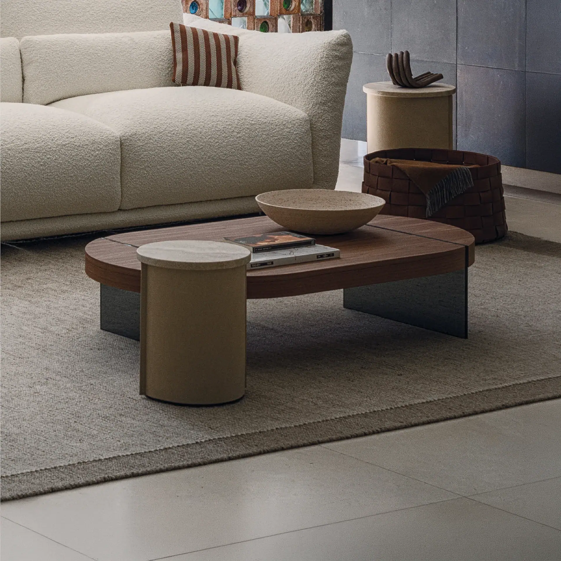A modern living room with a cream textured sofa, a wooden coffee table, and neutral-toned side tables on a light rug.