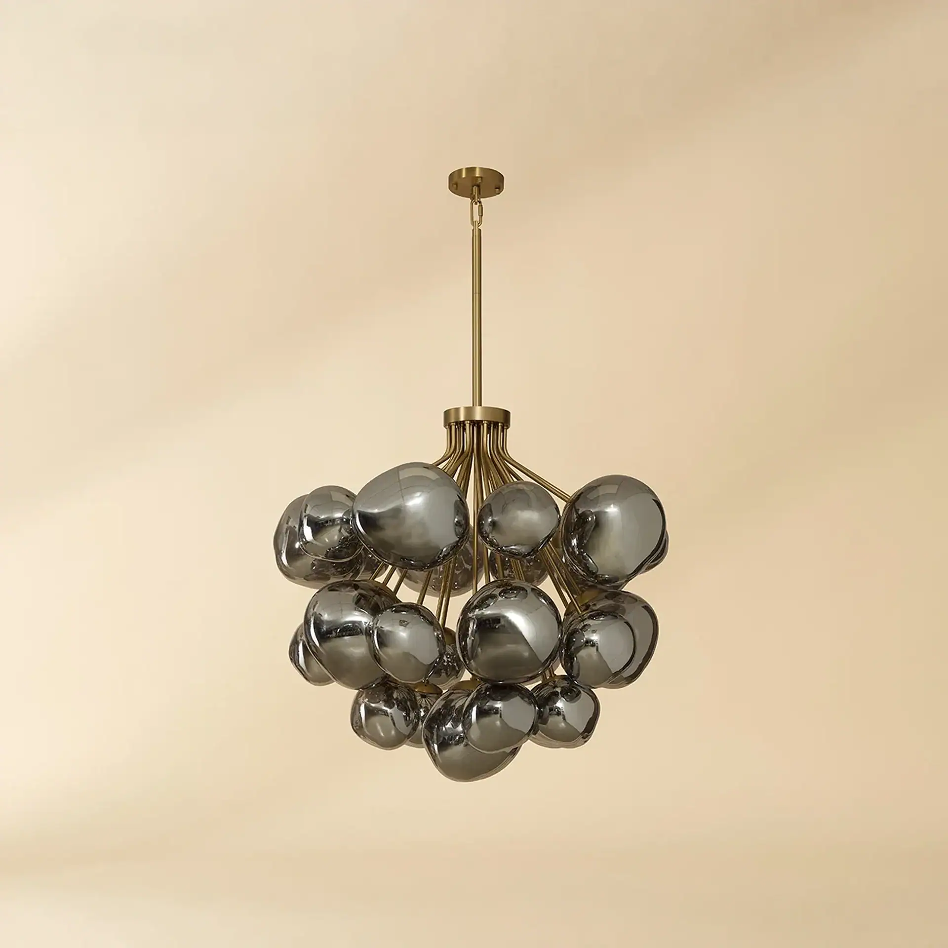 Modern chandelier with multiple smoked glass spheres and a brass frame, against a beige background.