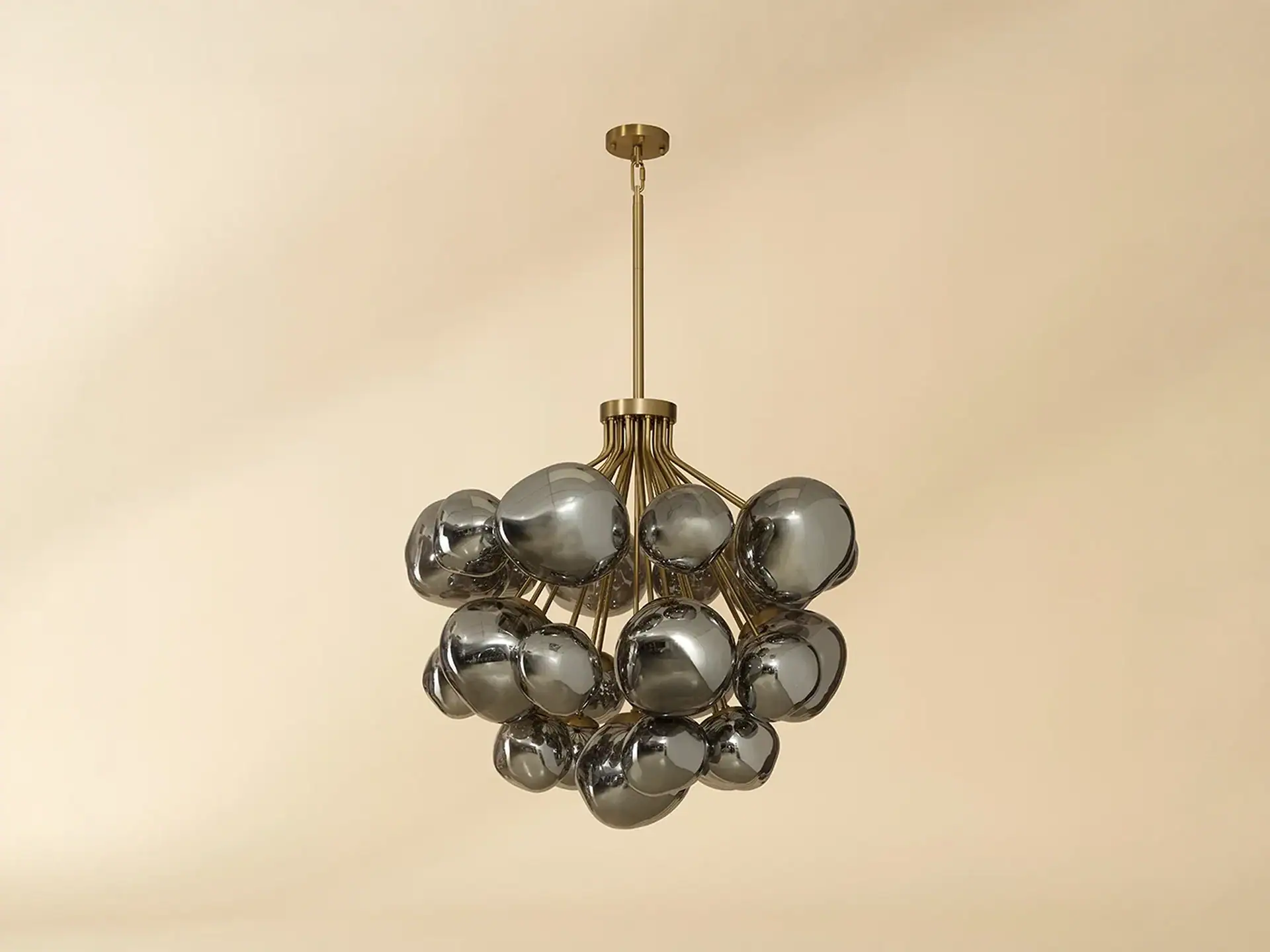 A modern chandelier with a brass frame and multiple reflective, irregularly shaped dark gray glass spheres, set against a light beige background.