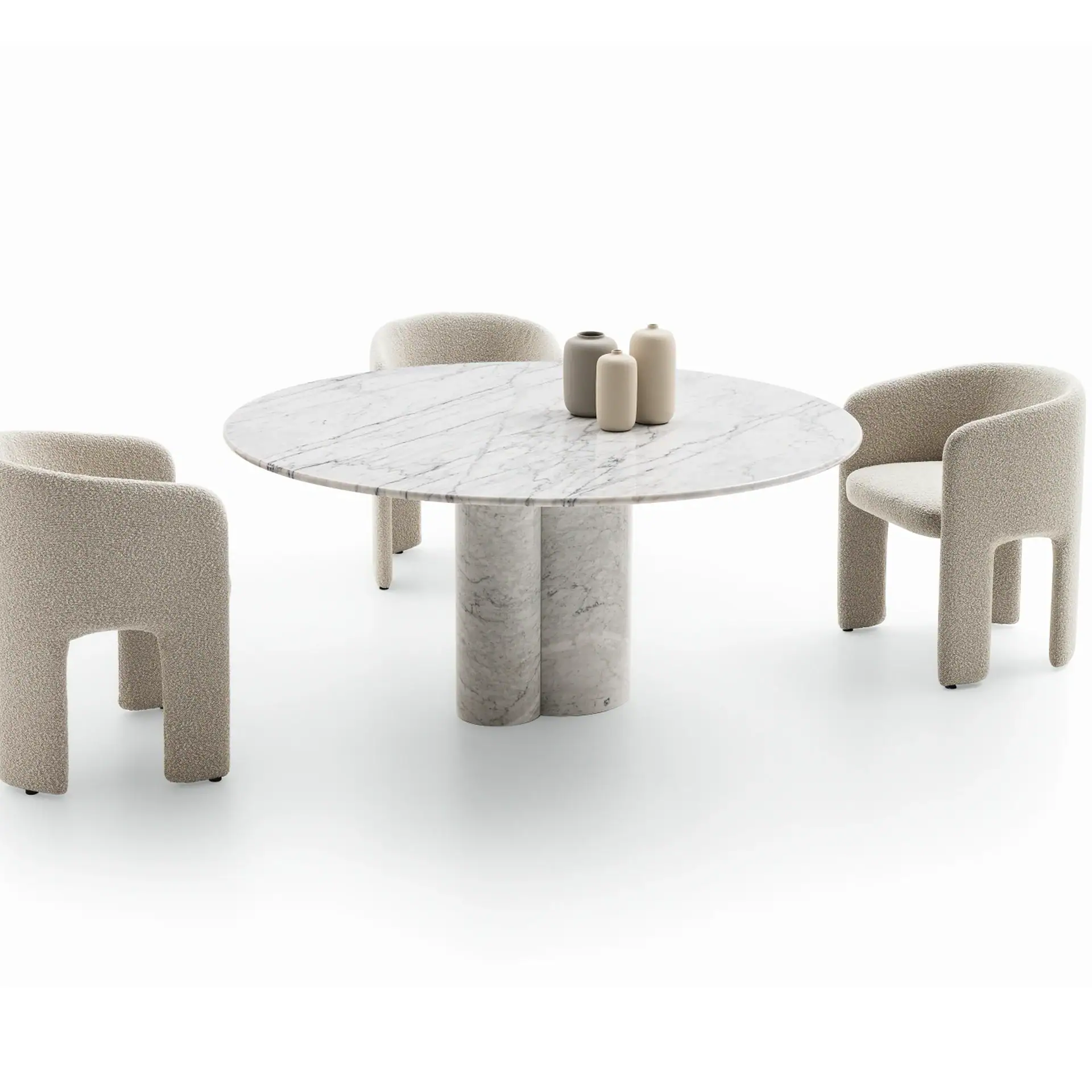 A round white marble dining table with two cylindrical bases, surrounded by three light beige bouclé chairs. Three ceramic vases sit on the table.