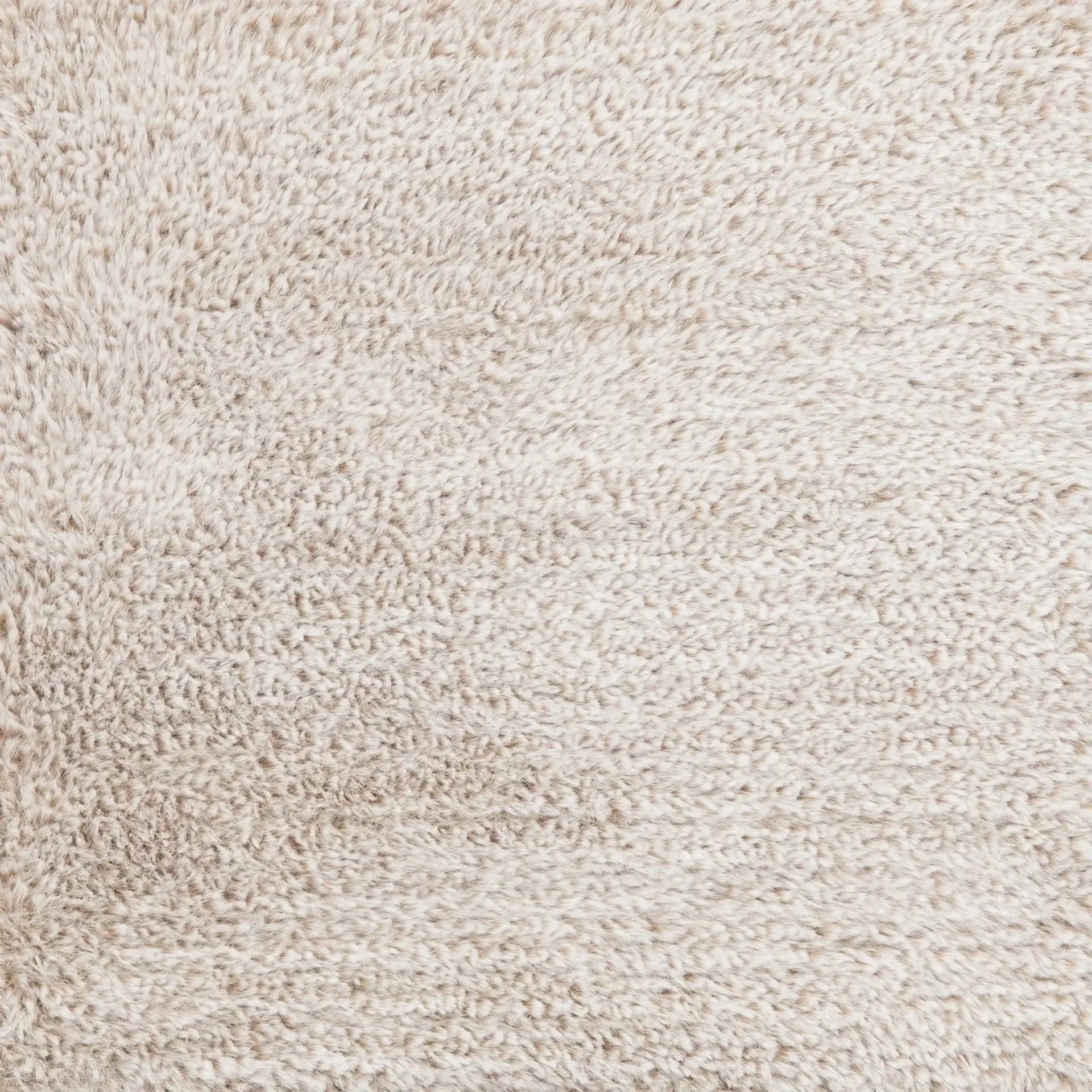 Close-up of a cream-colored, shaggy textured fabric or carpet.