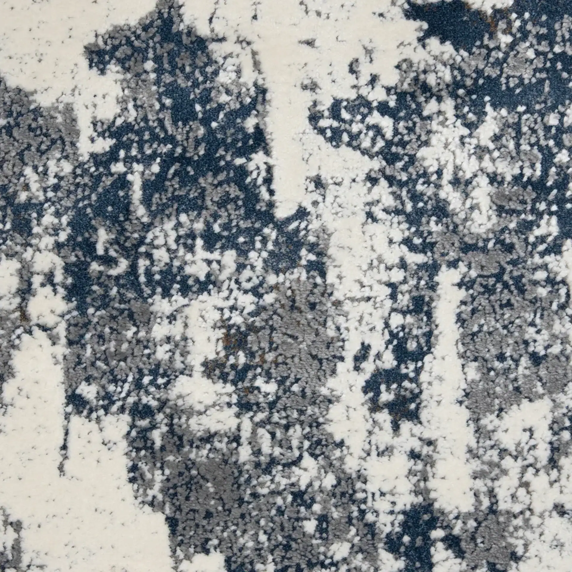 Close-up of an abstract rug pattern with blotches of off-white, dark blue, and grey.