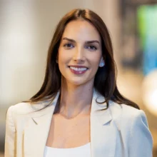 team-camila-harasic-2026 Headshot of a smiling young woman with long dark hair, wearing a light blazer and stud earrings.