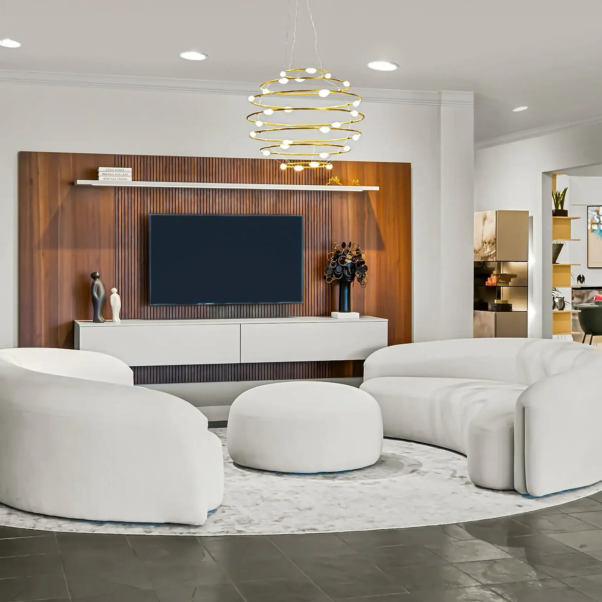 A modern living room with a curved white sofa, armchair, and ottoman on a circular rug. A TV is mounted on a slatted wooden wall above a white console, beneath a gold chandelier.