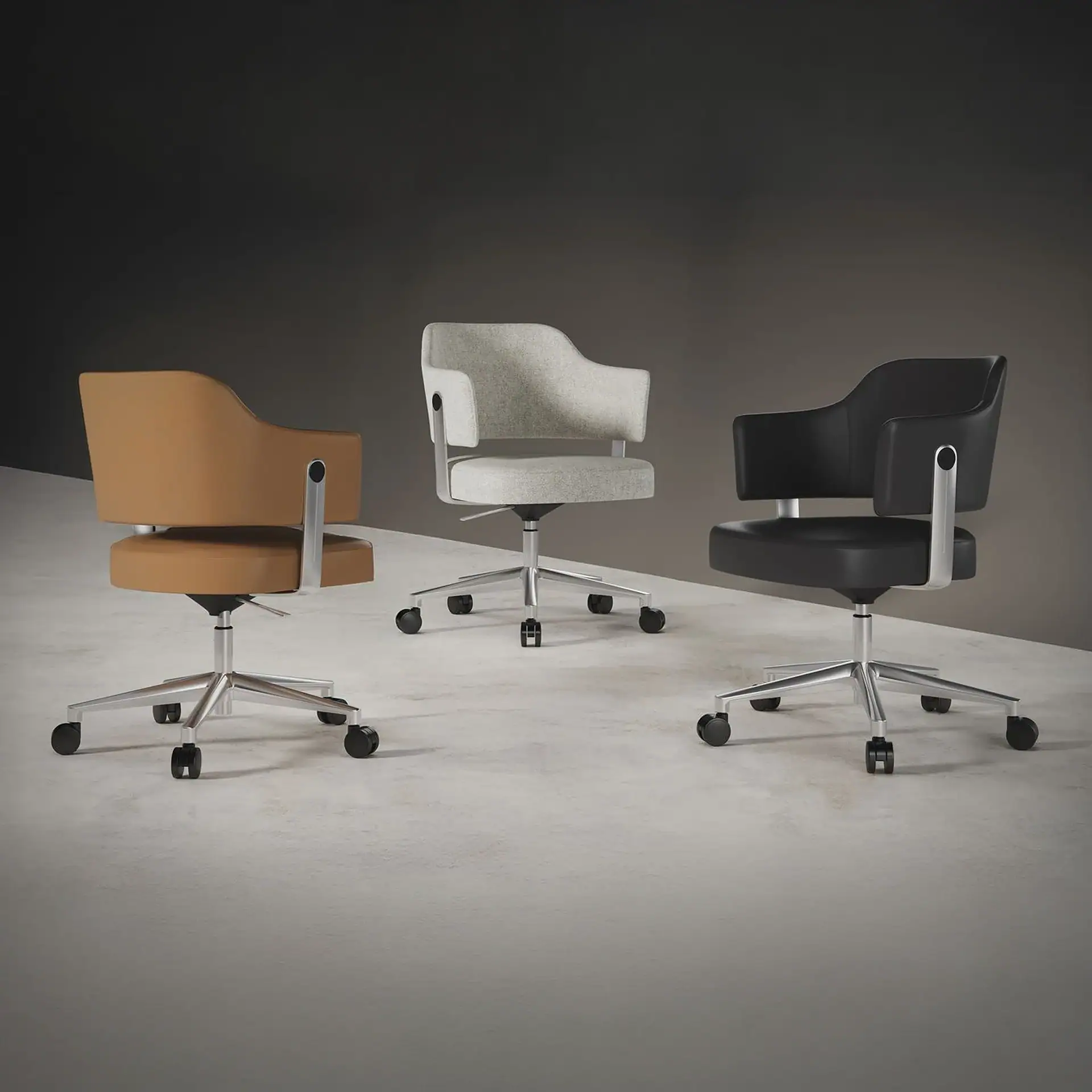 Three modern office chairs: one tan leather, one light gray fabric, and one black leather, all with silver bases and casters, on a gray floor.