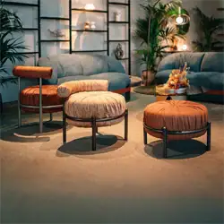 Sklar Furnishings ottomans with plush fabric and black metal bases in a modern living room.