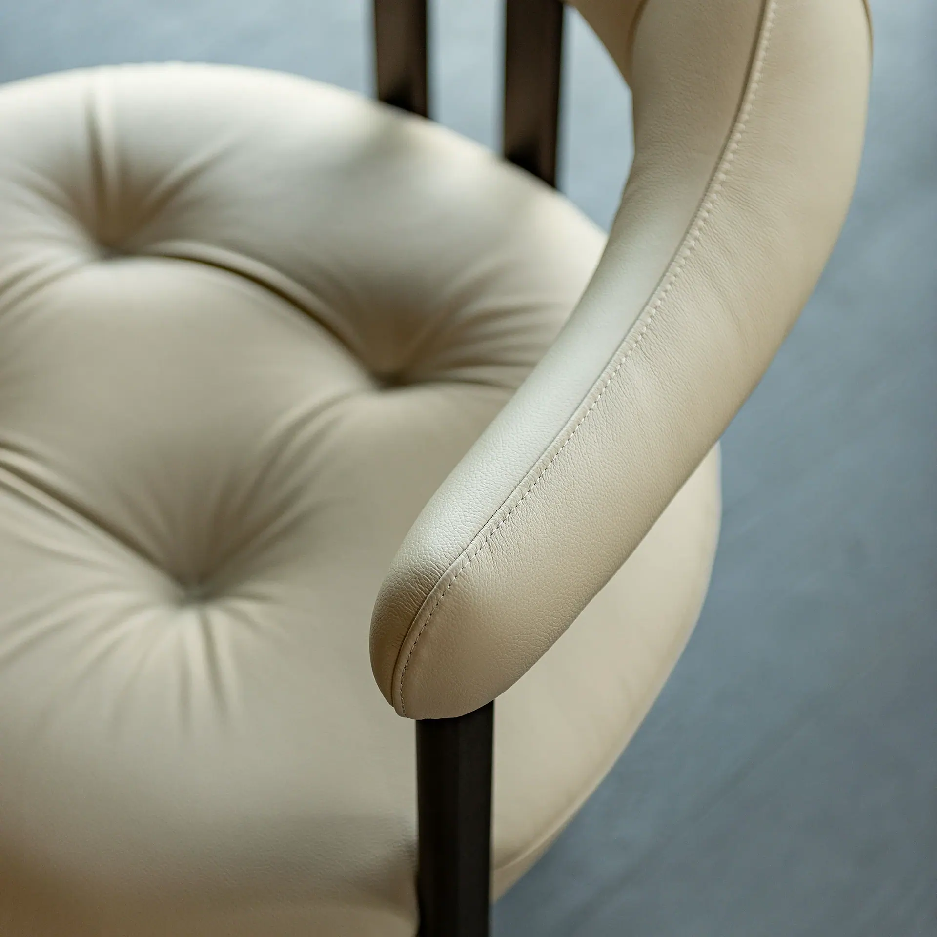 Greta Dining Armchair close view showing beige upholstery and curved arm.